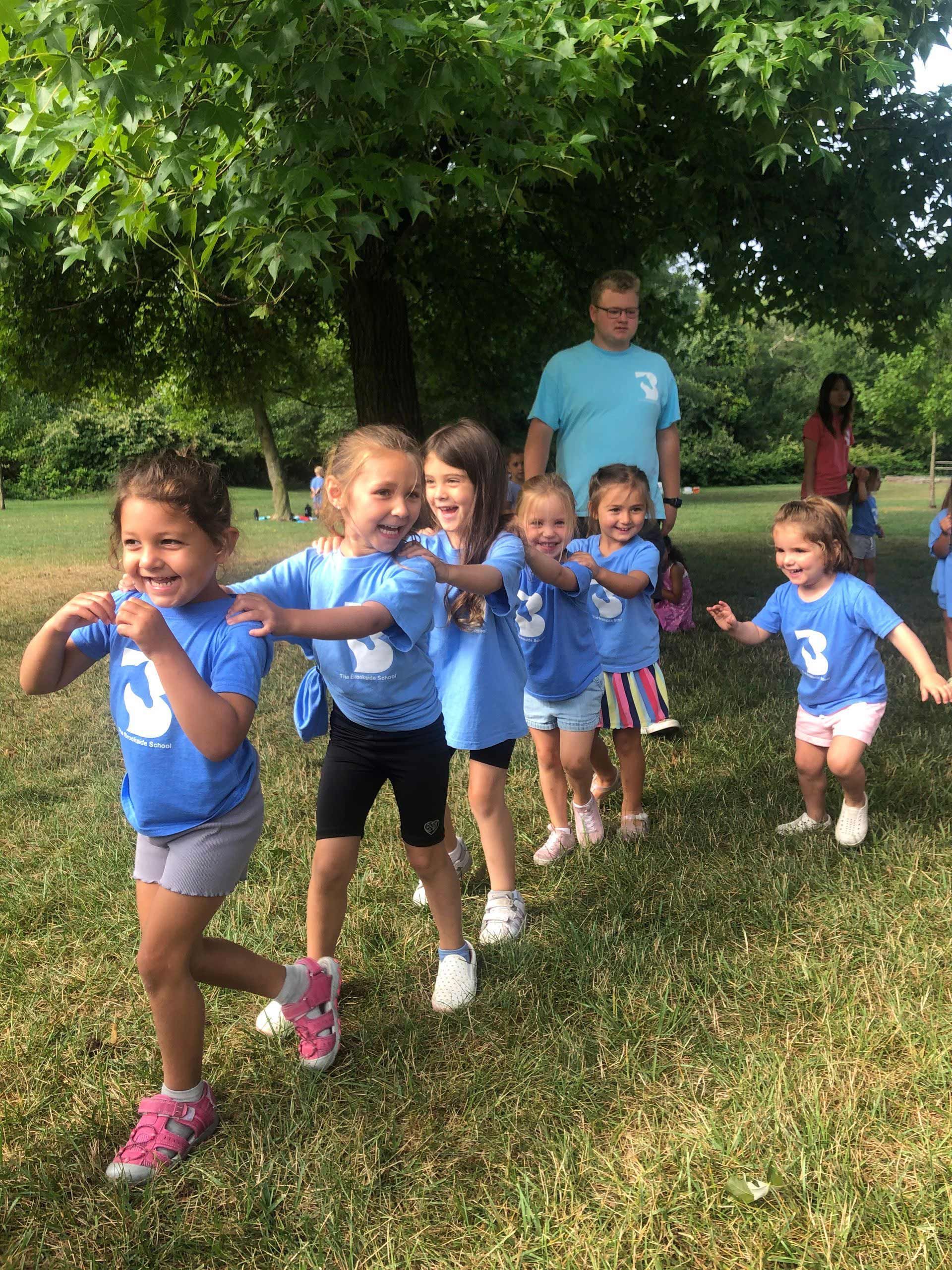 A group of young girls are walking in a line in a park.