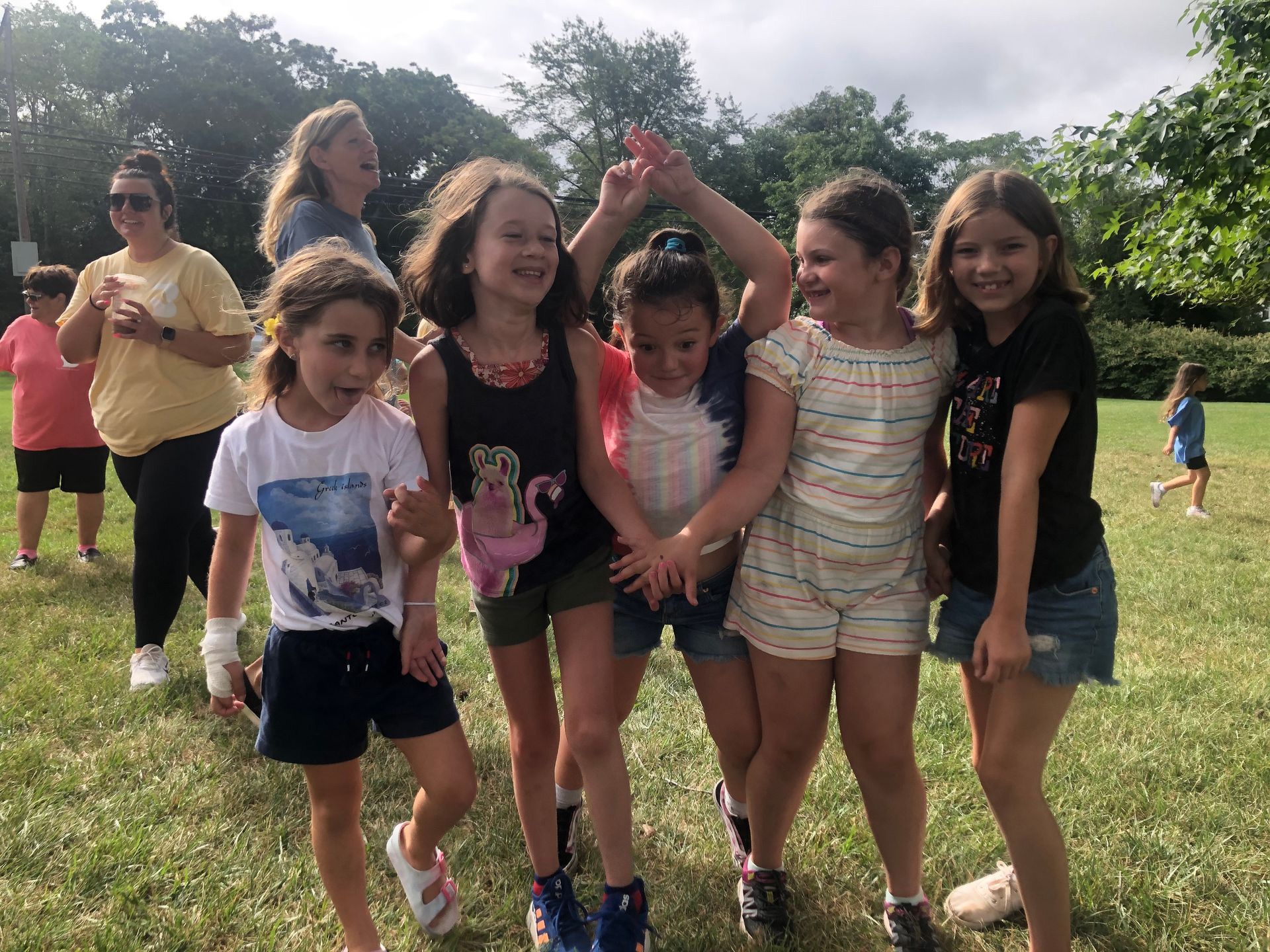 A group of young girls are standing in a field holding hands.