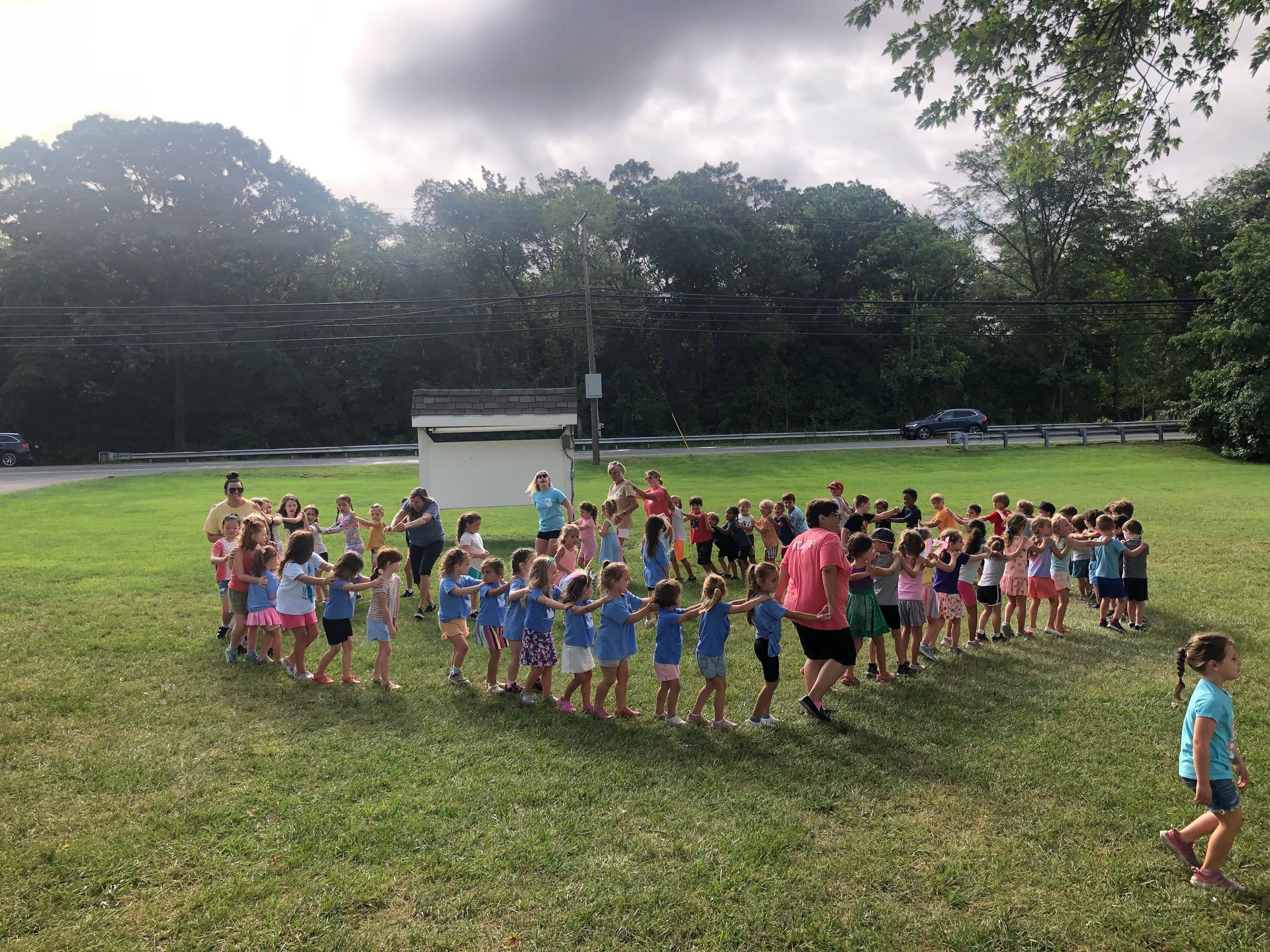 A group of children are holding hands in a circle in a field.