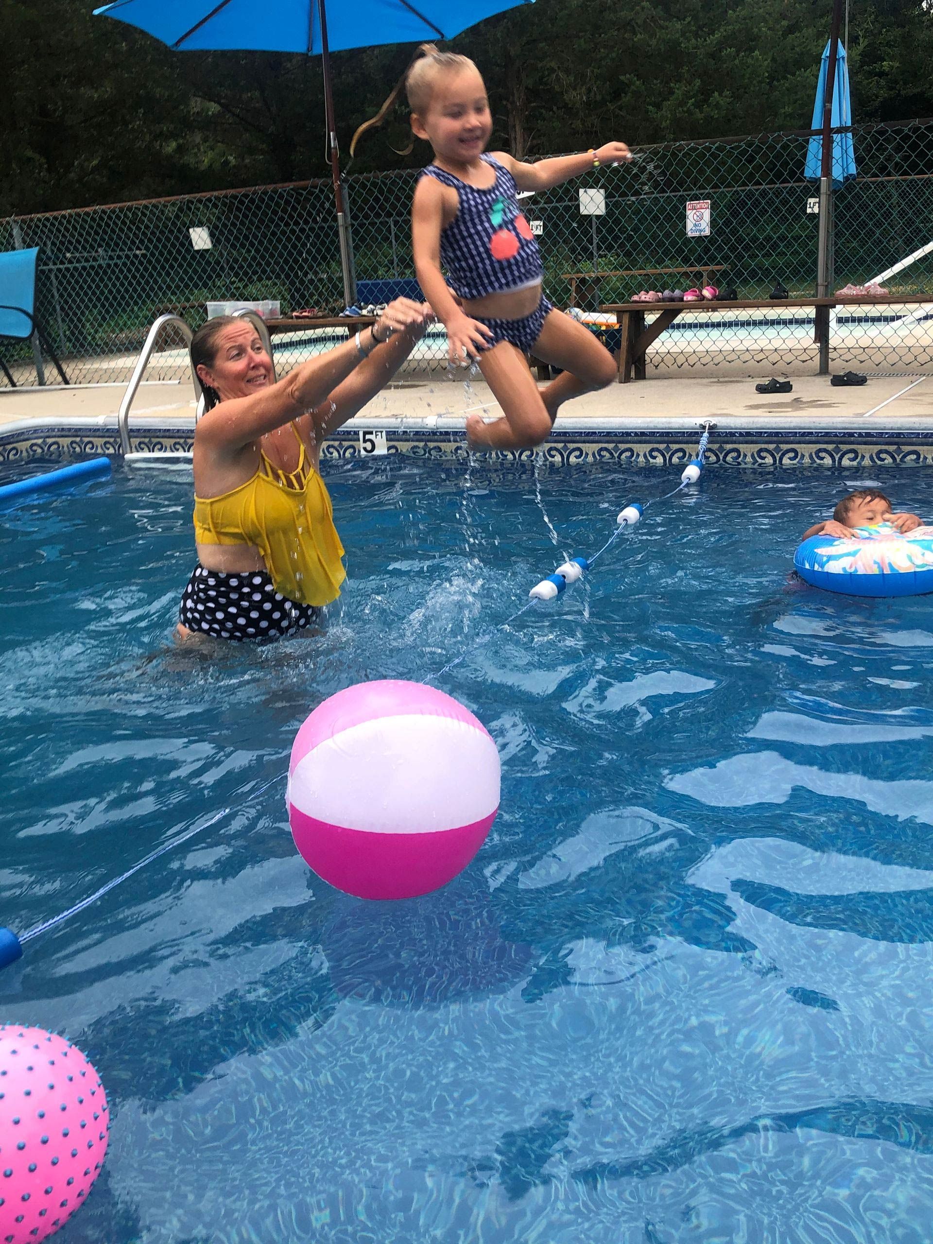 A woman is holding a little girl in a swimming pool.