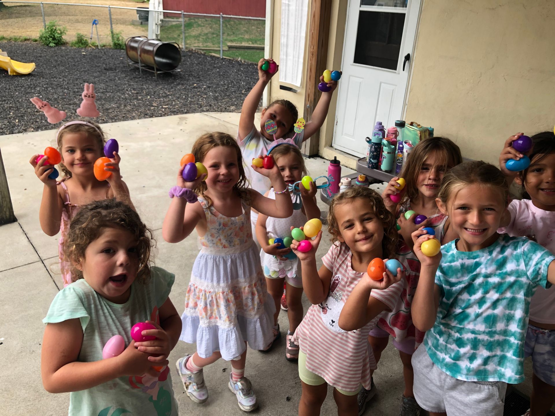 A group of young girls are holding easter eggs in their hands.