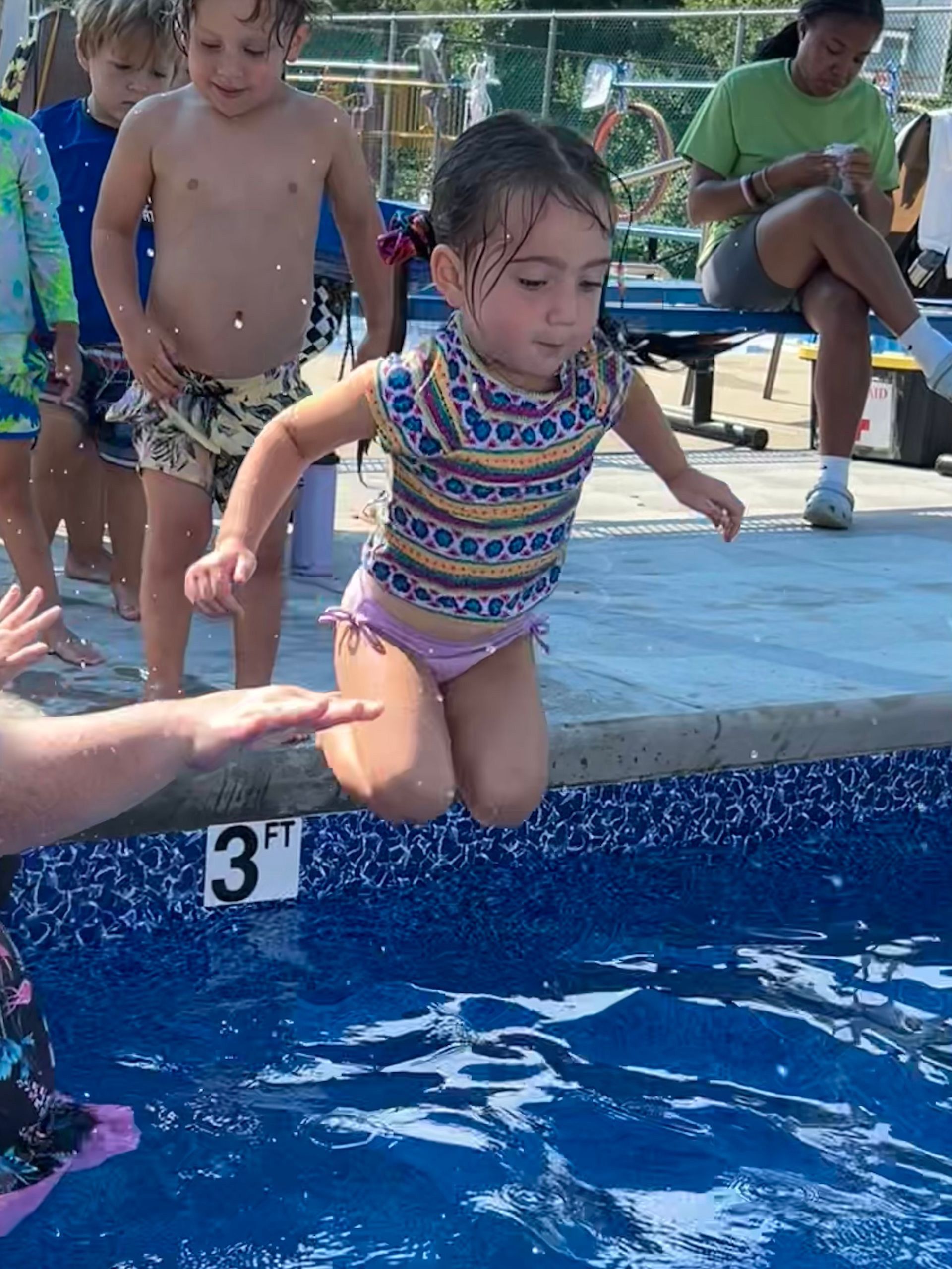 A little girl is jumping into a swimming pool.