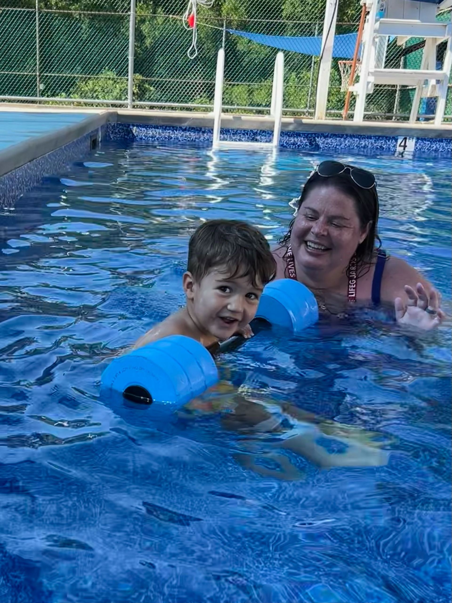 A woman is teaching a young boy how to swim in a swimming pool.