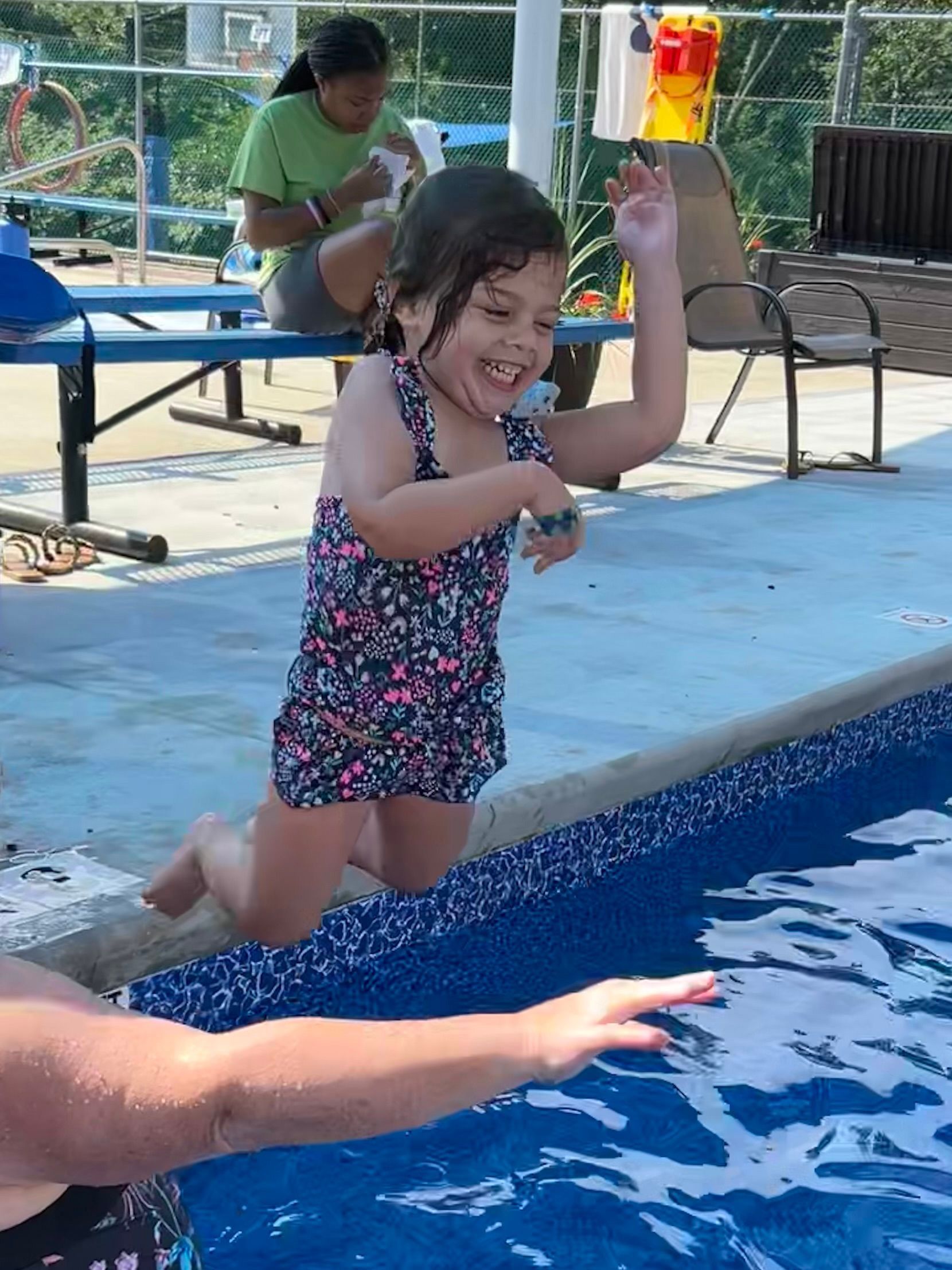 A little girl is jumping into a swimming pool.