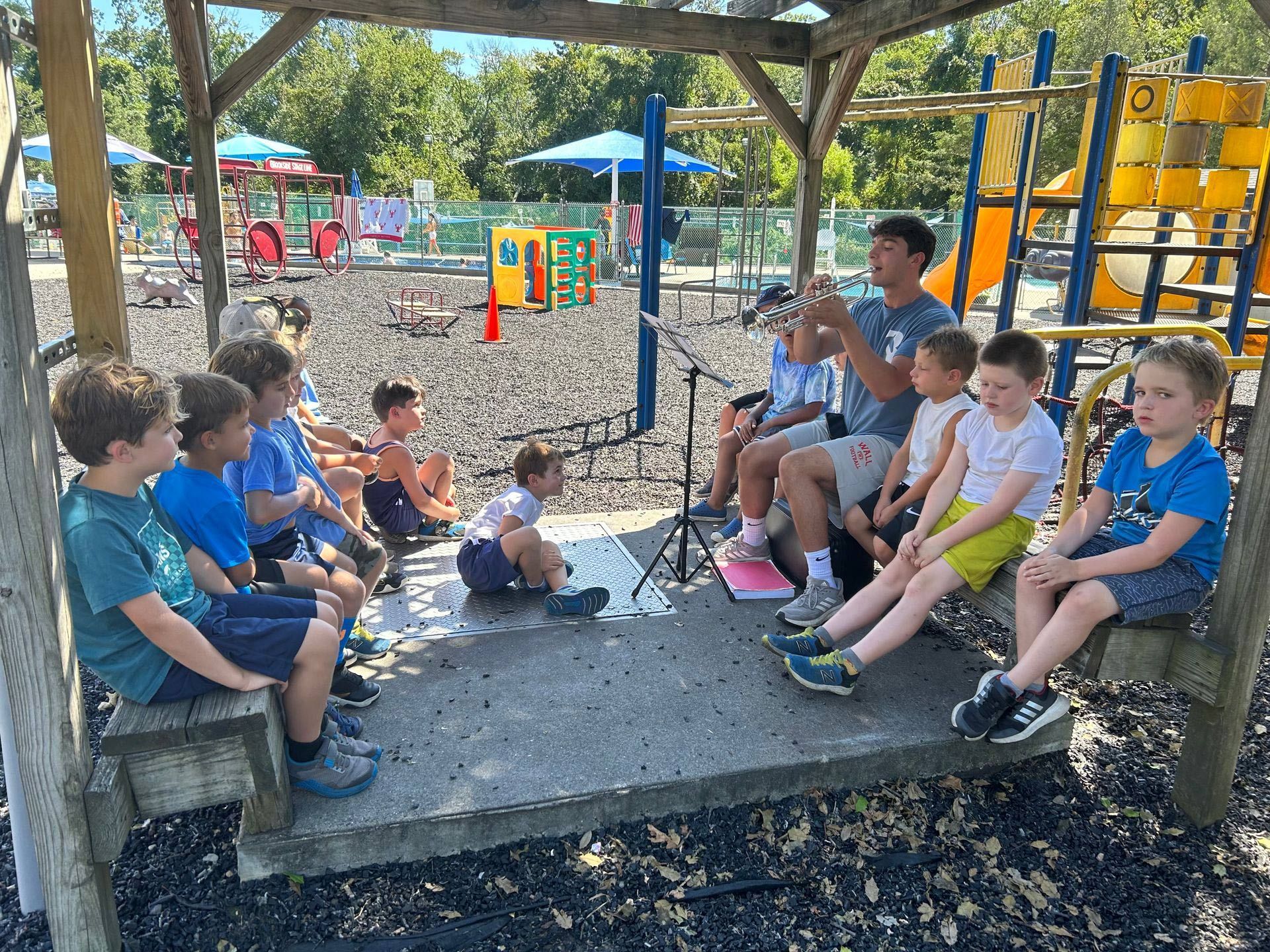 A group of young boys are sitting under a gazebo at a playground.