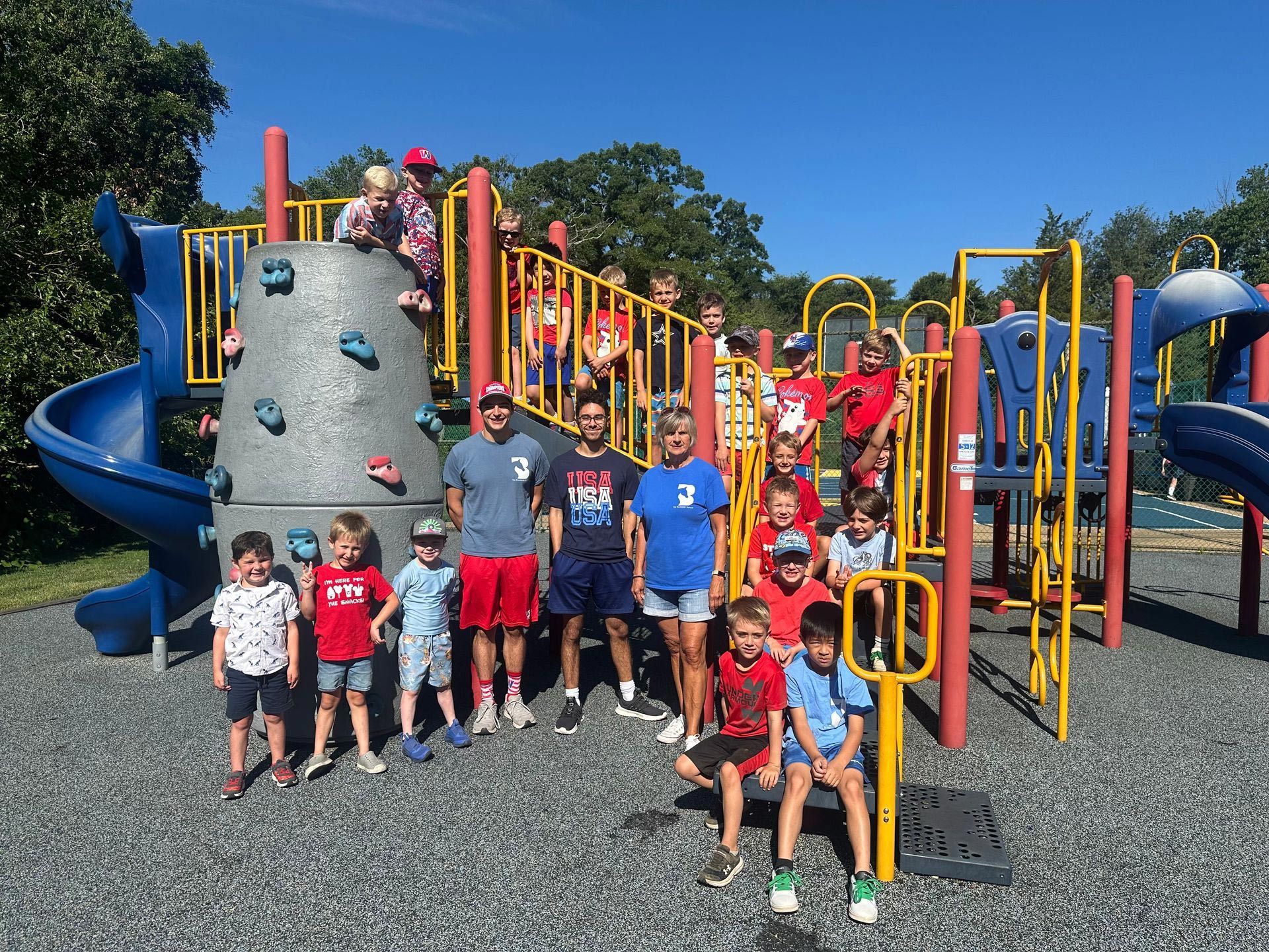 A group of children are posing for a picture in front of a playground.