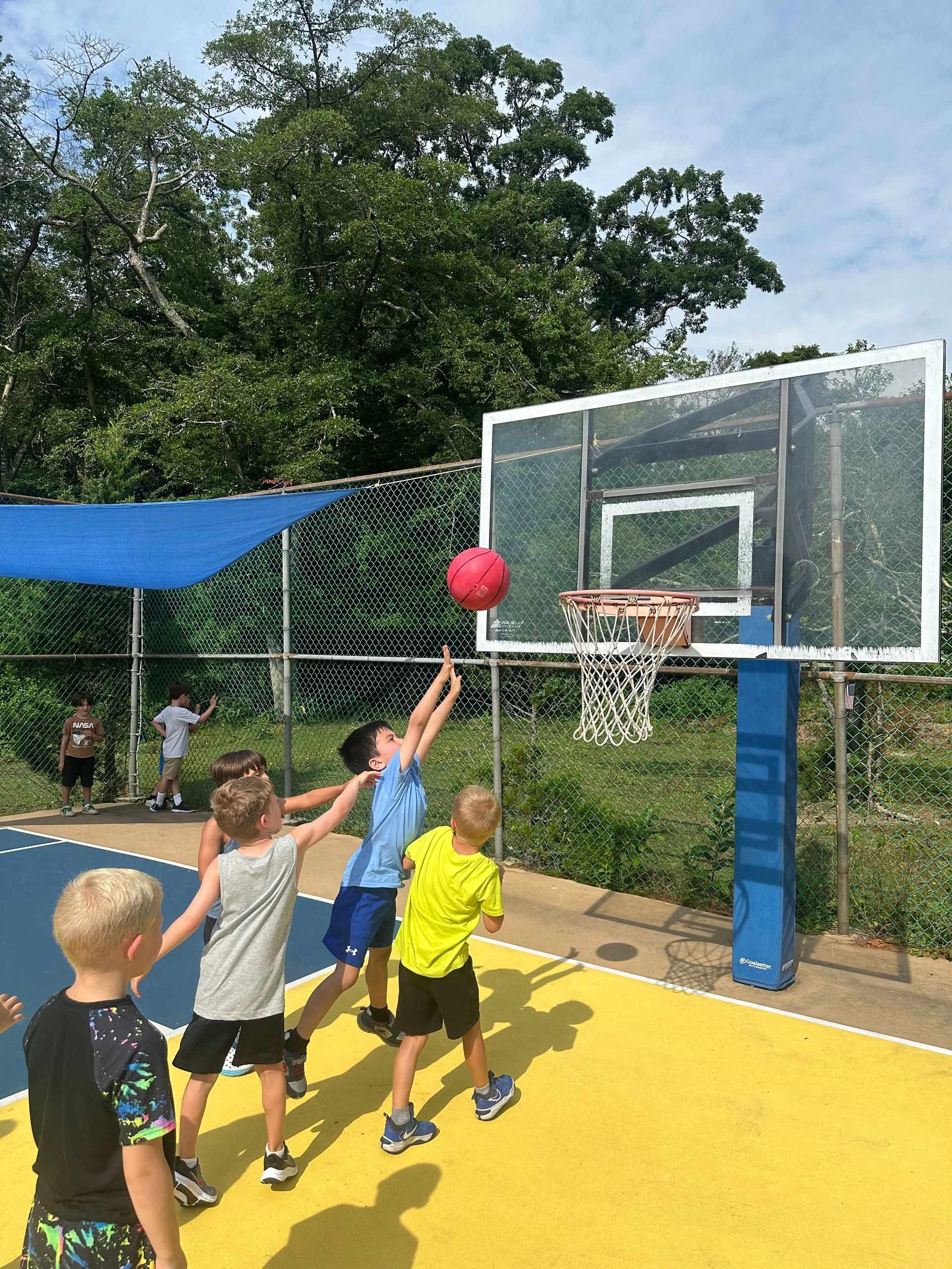 A group of young boys are playing basketball on a court.