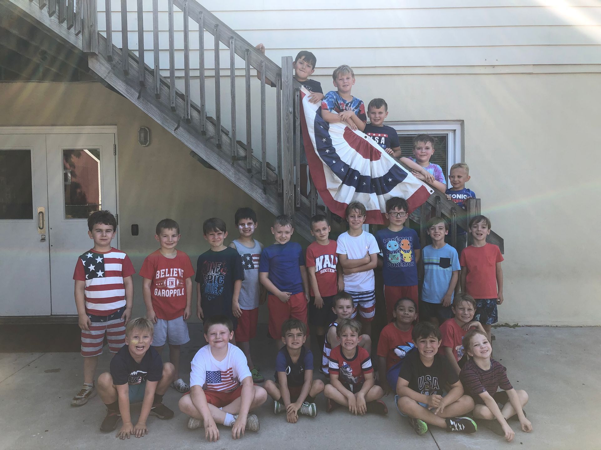 A group of children are posing for a picture in front of stairs.