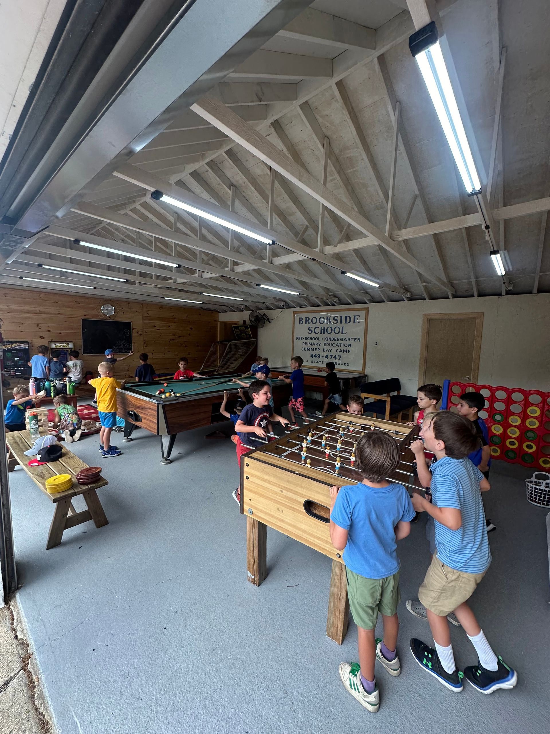 A group of children are playing foosball in a large room.