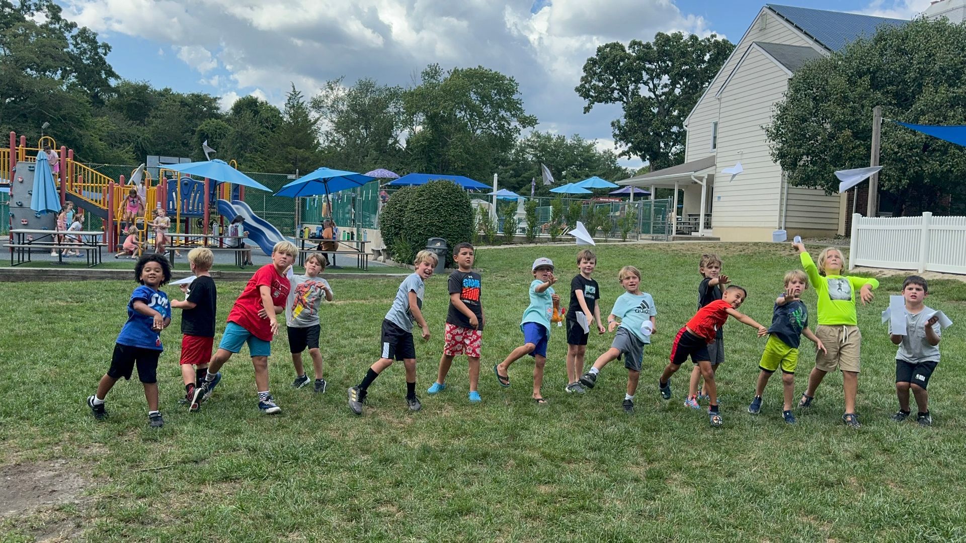 A group of children are standing in a row in a grassy field.