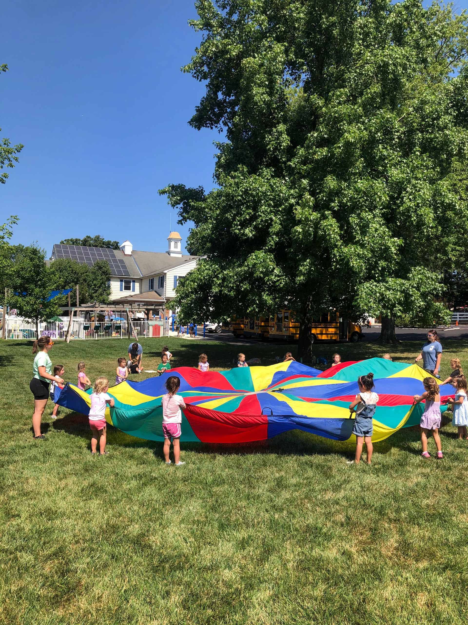 A group of children are playing with a parachute in a park.