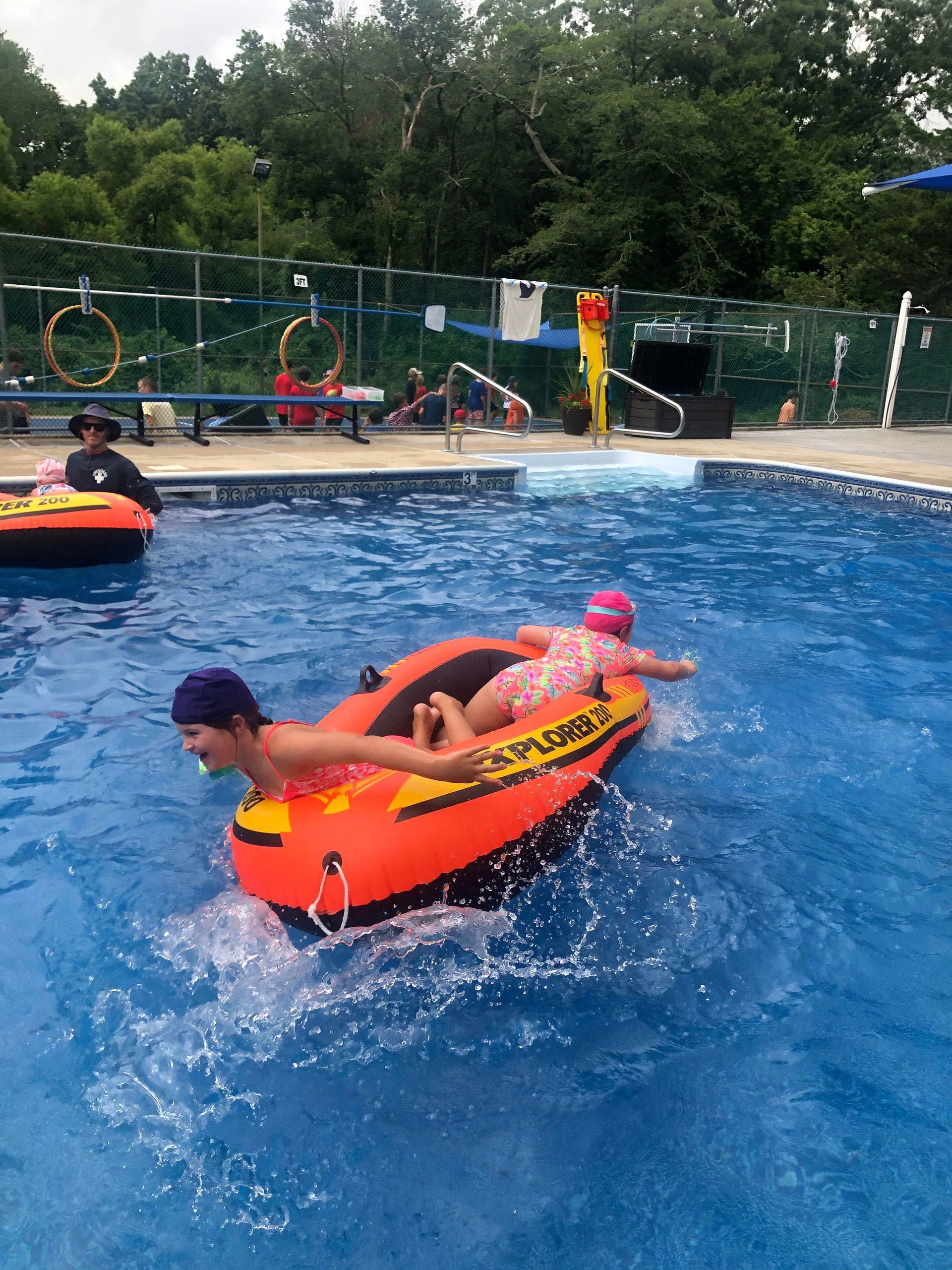 A boy and a girl are floating on a tube in a swimming pool.