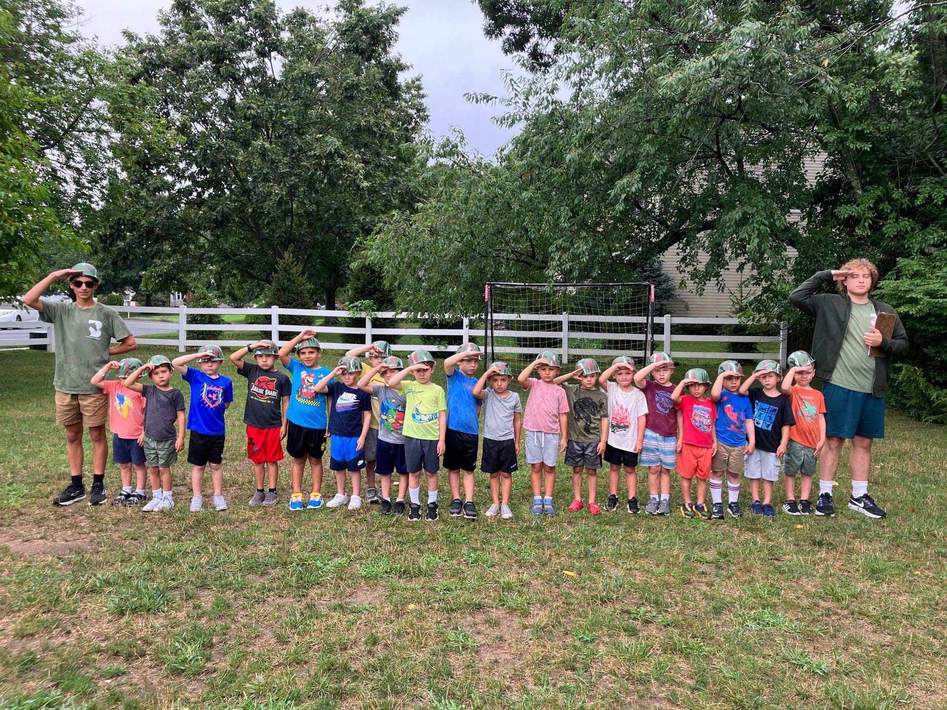 A group of children are saluting in a field.