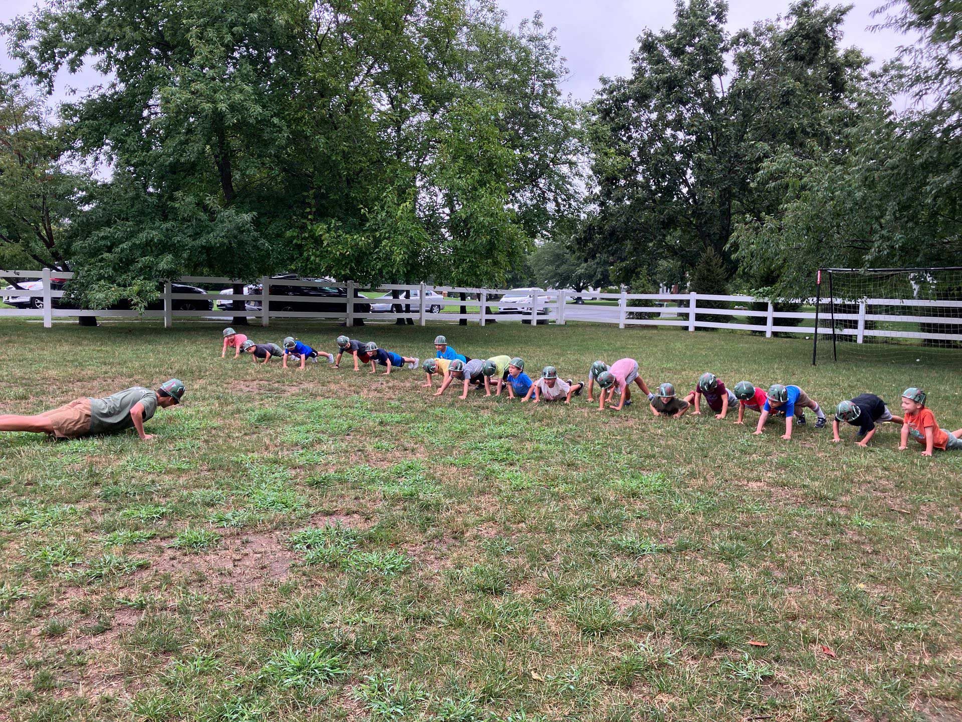 A group of people are doing push ups in a field.