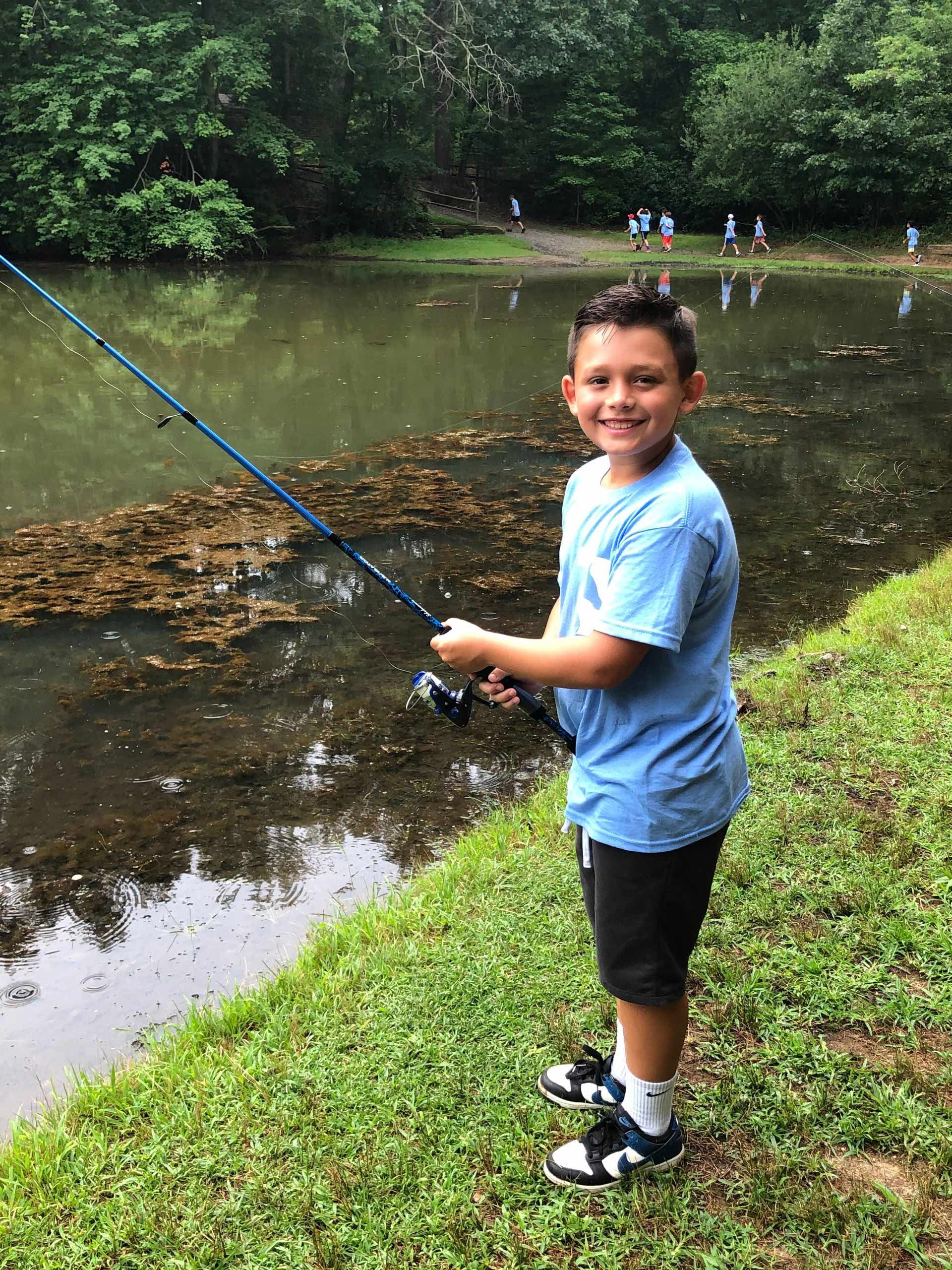 A young boy is fishing in a lake with a fishing rod.