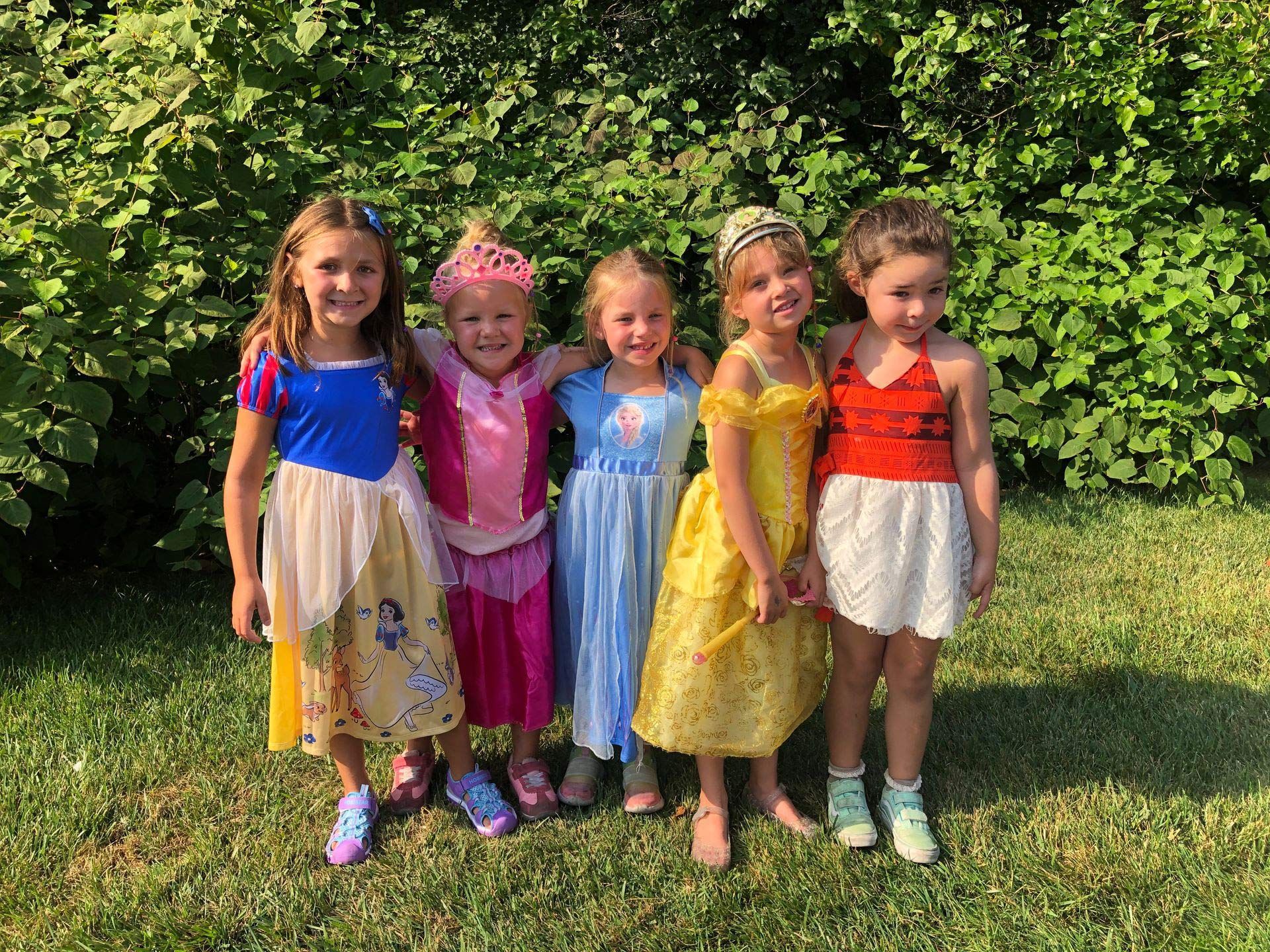 A group of young girls dressed as princesses are posing for a picture.