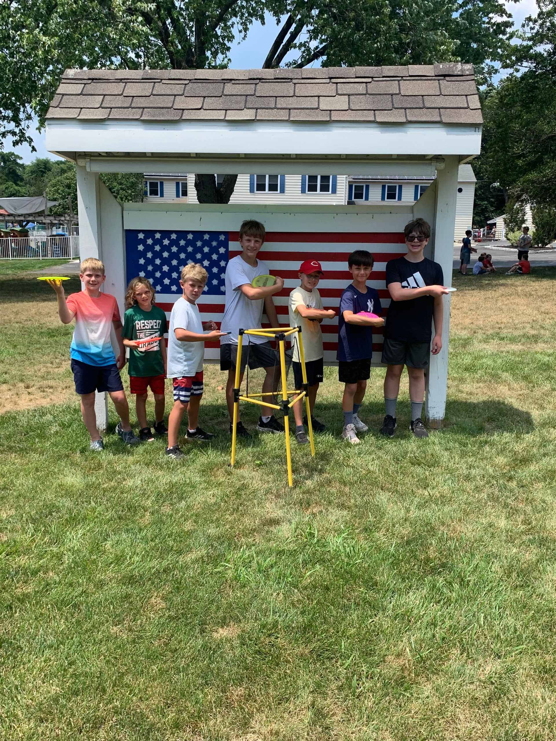 A group of young boys are standing in front of an american flag.