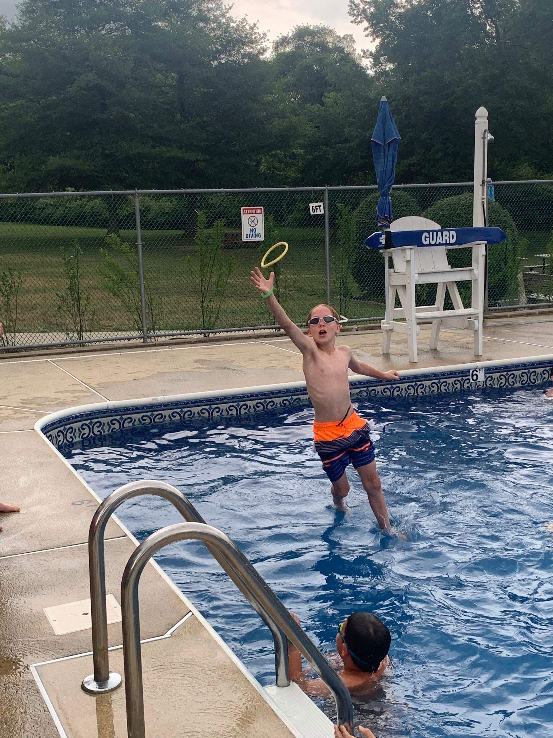 A young boy is playing with a frisbee in a swimming pool.