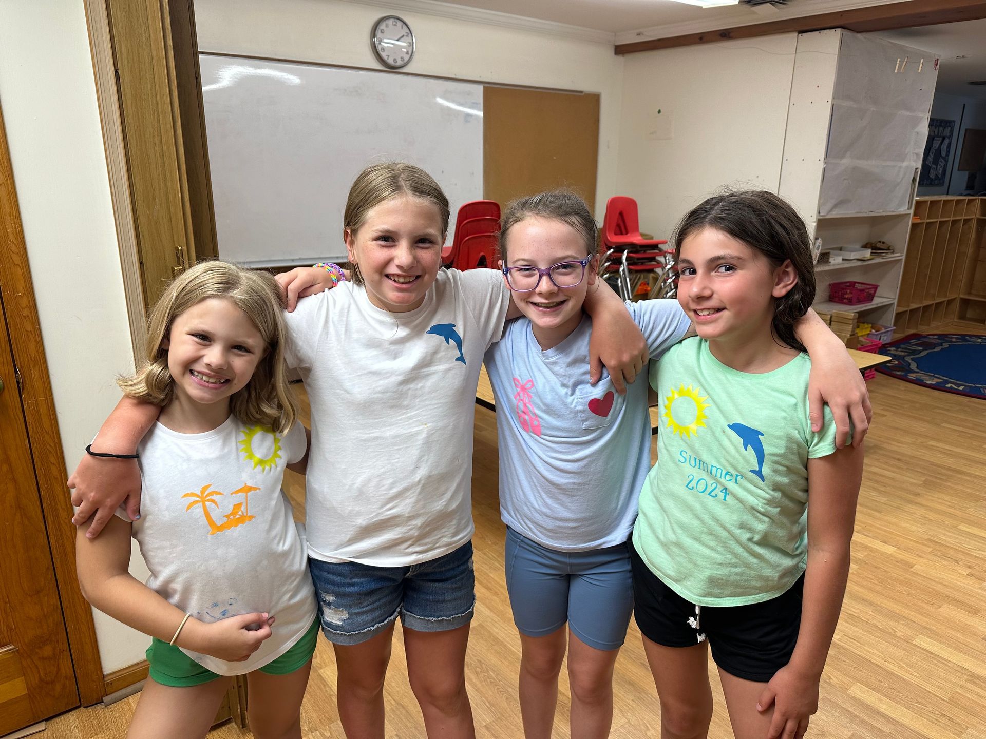 Four young girls are posing for a picture together in a room.