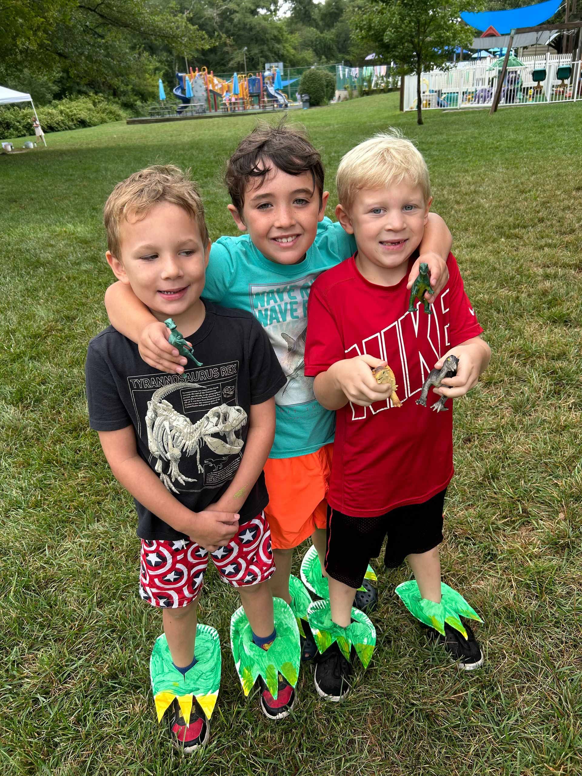 Three young boys are posing for a picture in a park.