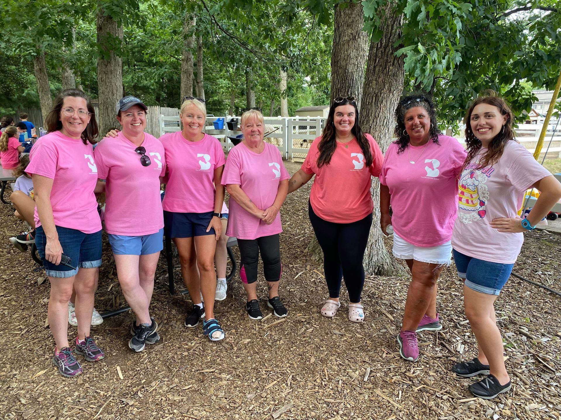 A group of women wearing pink shirts are posing for a picture.