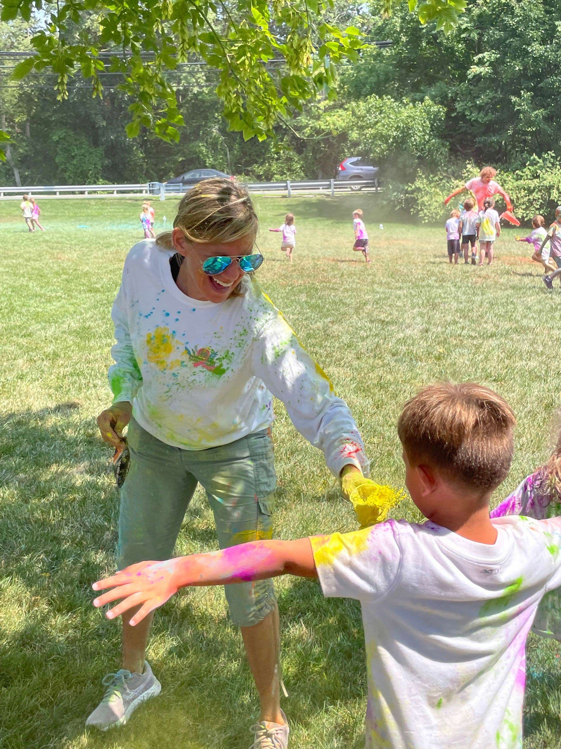 A woman and a boy are playing with colored powder in a field.