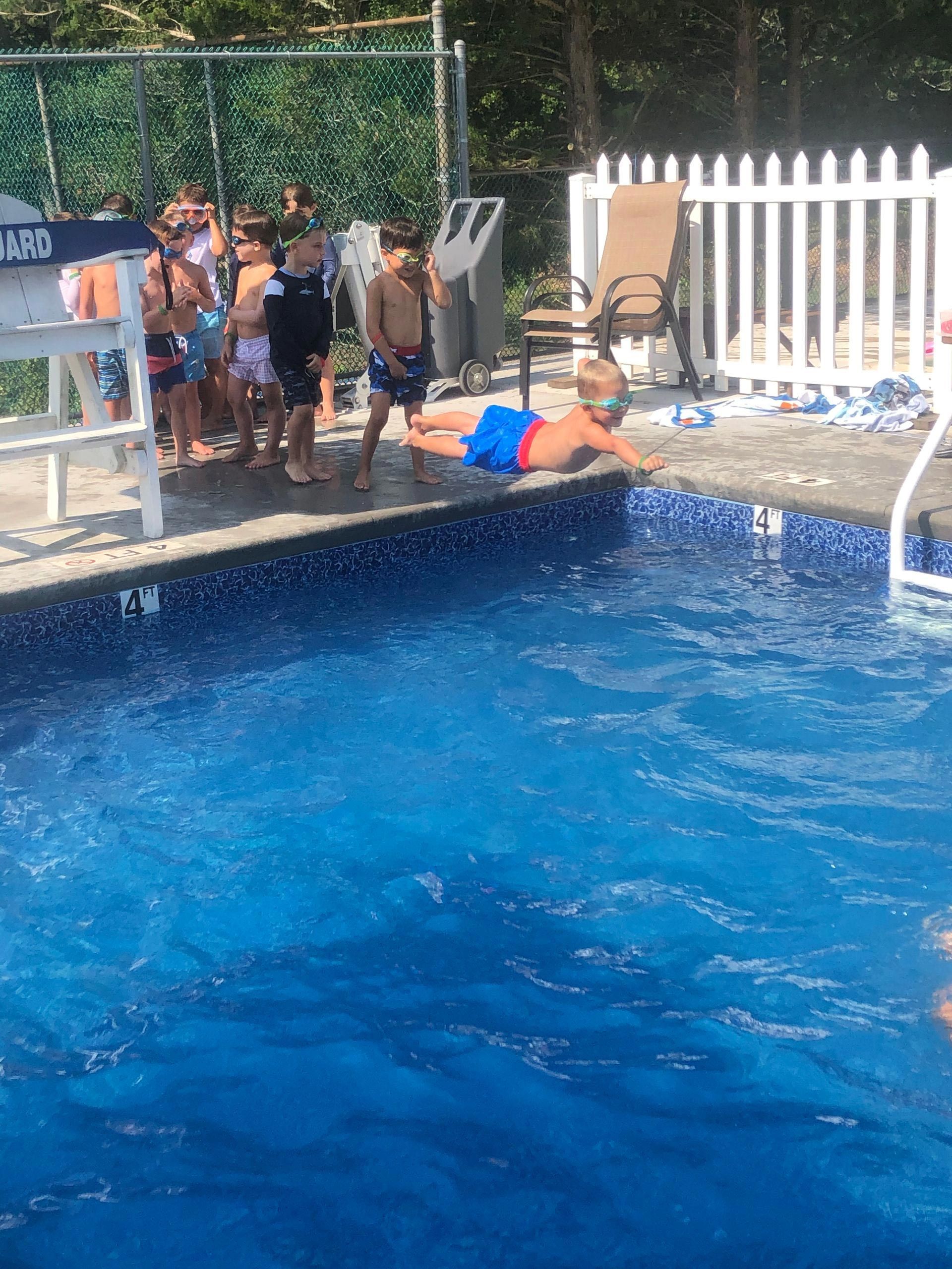 A group of people are standing around a swimming pool.