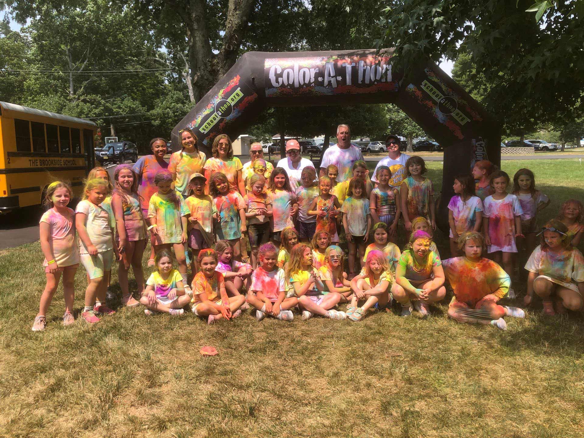 A group of children are posing for a picture in front of an inflatable arch.