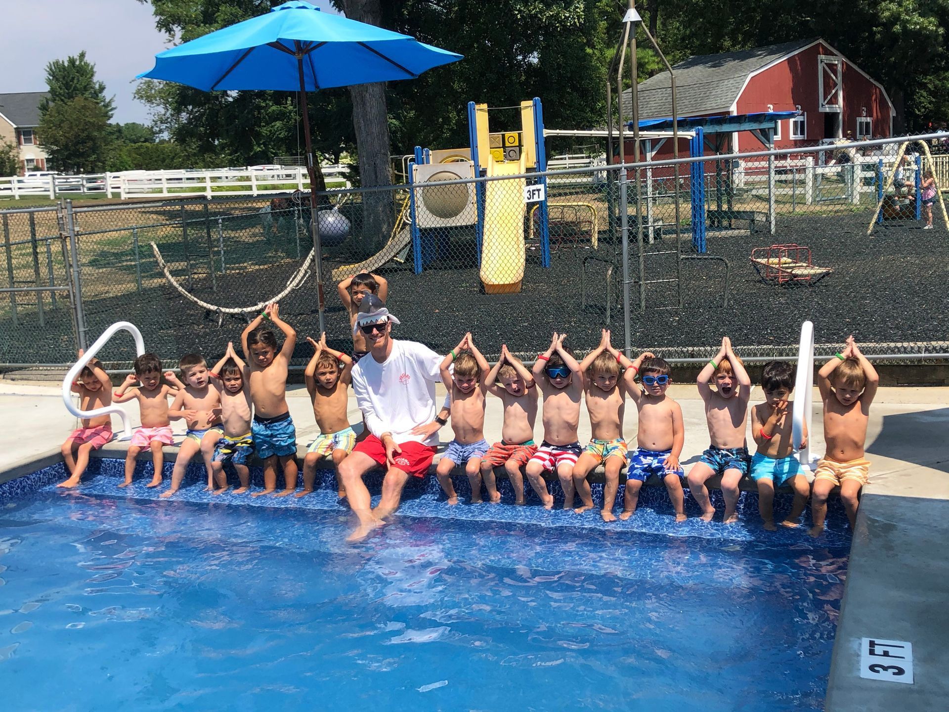 A group of children are sitting on the edge of a swimming pool.