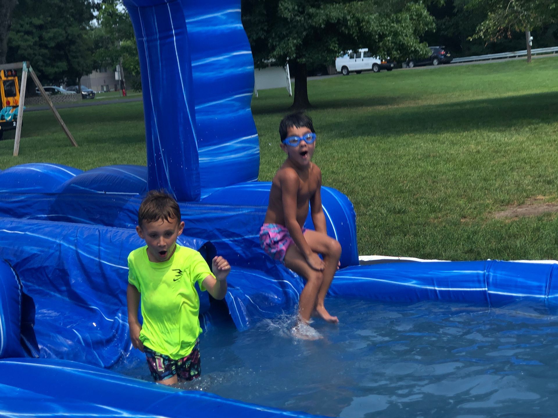 Two young boys are playing in an inflatable water slide.