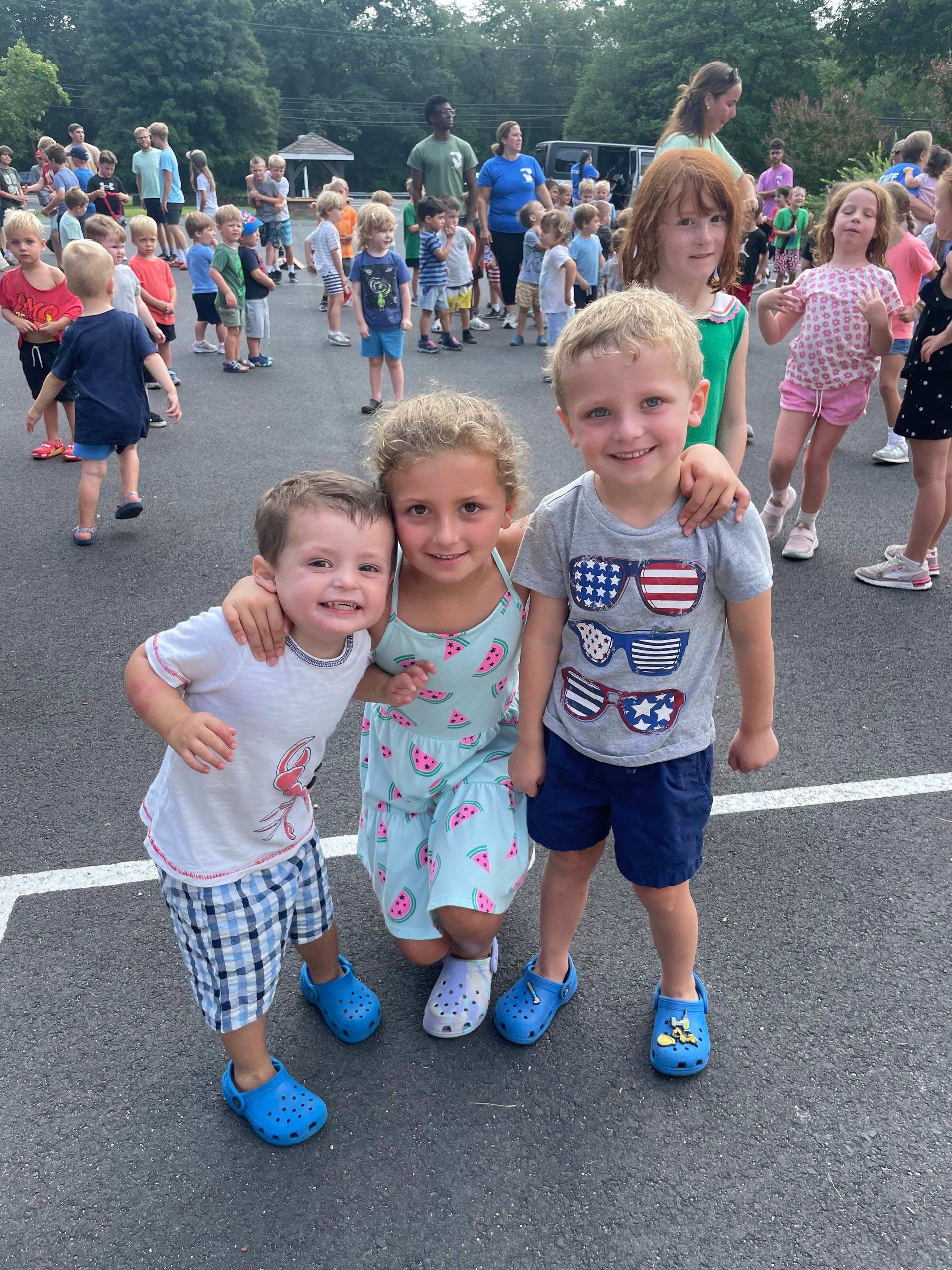 A group of children are posing for a picture in a parking lot.