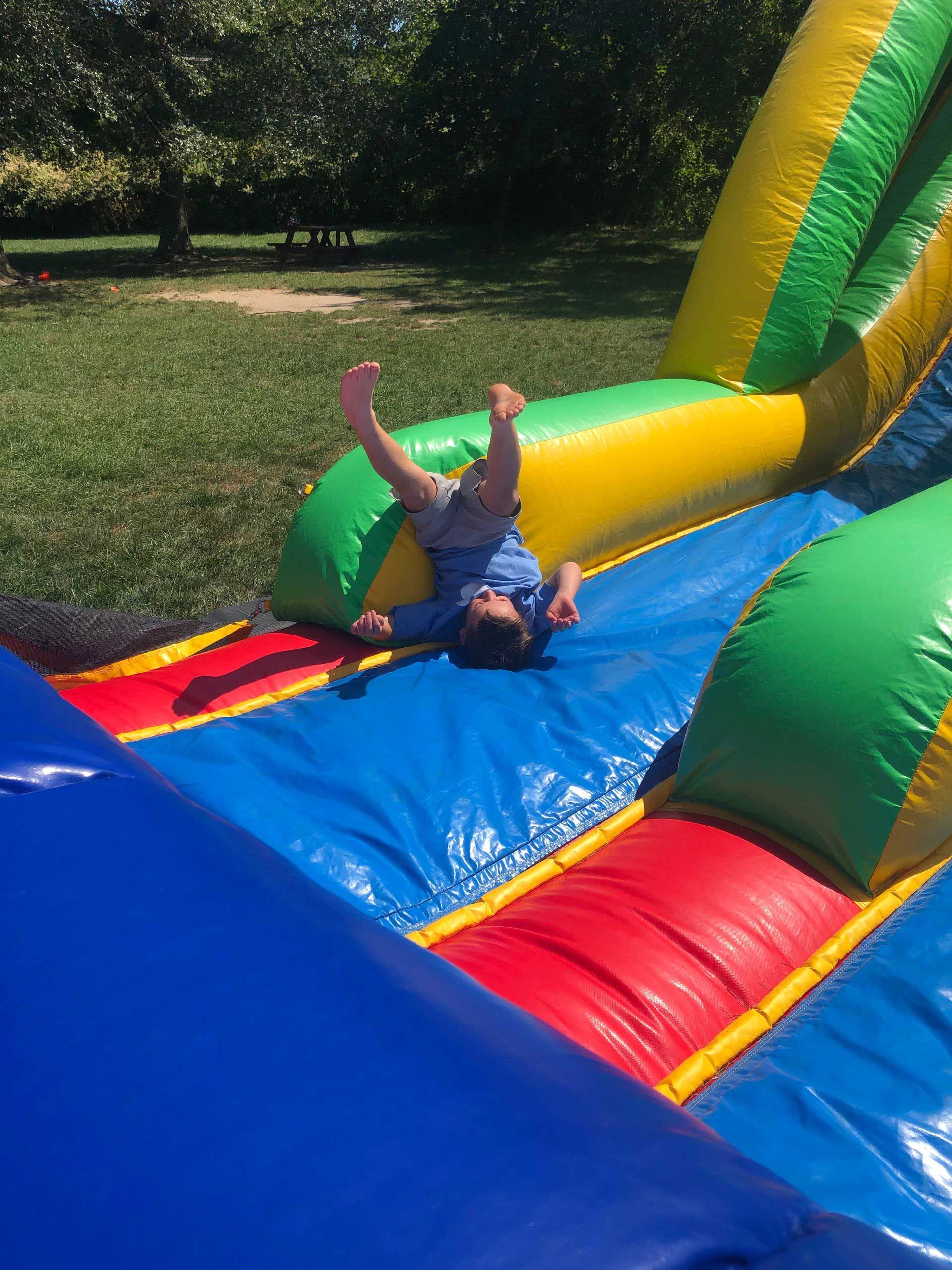 A little boy is laying on his back on an inflatable slide.