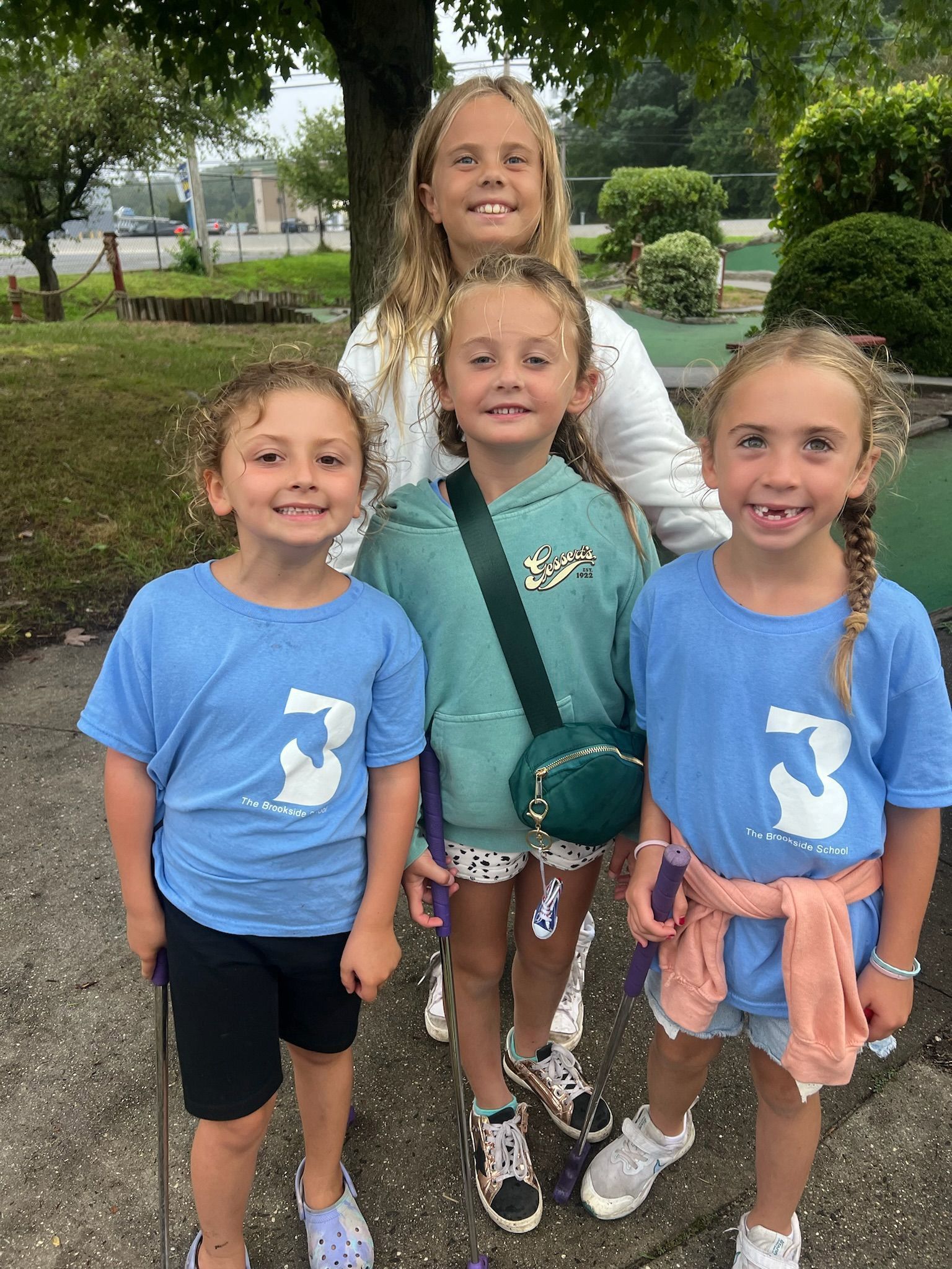 A group of young girls are standing next to each other on a sidewalk.