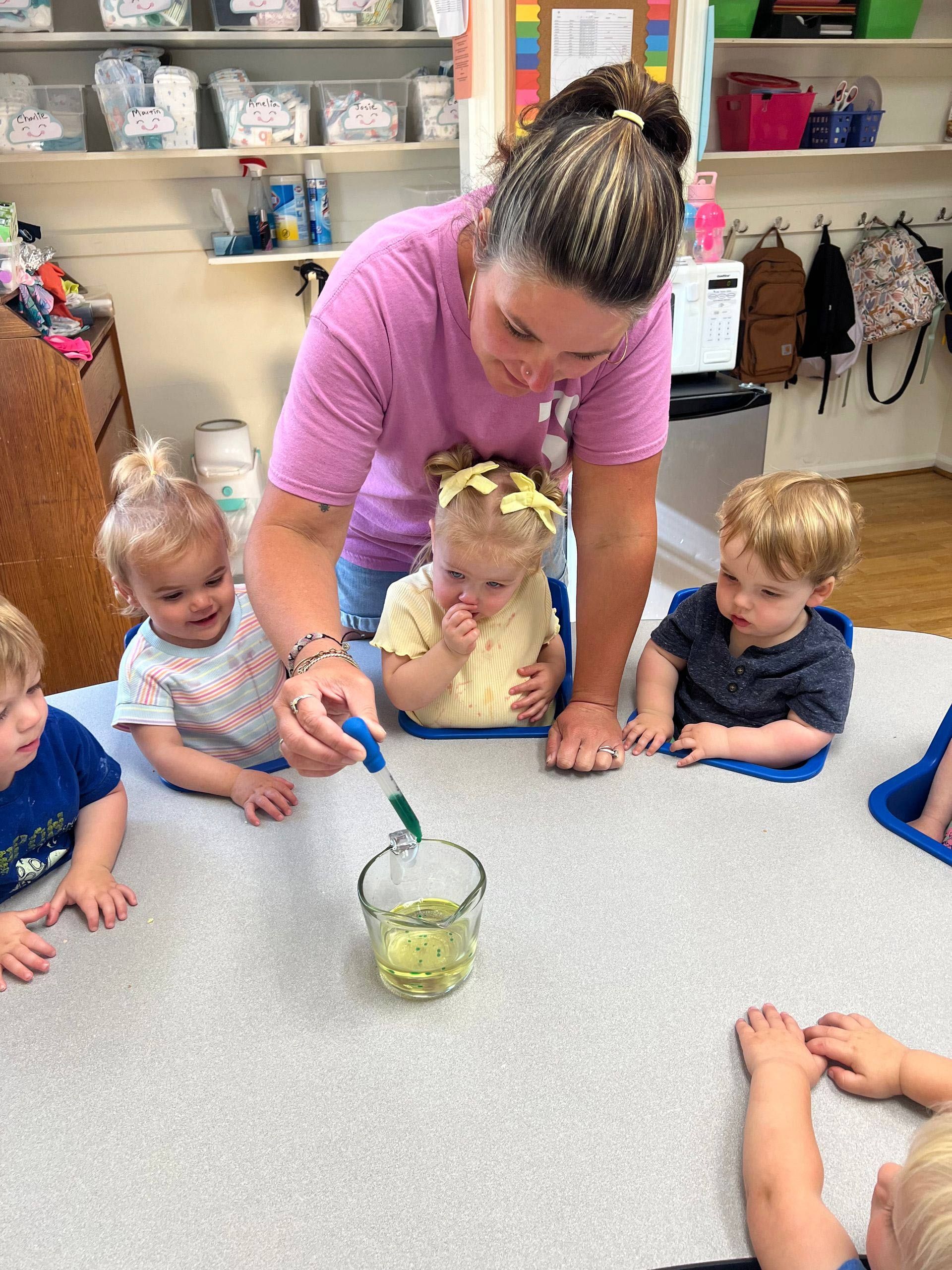 A woman is teaching a group of children how to use a pipette.