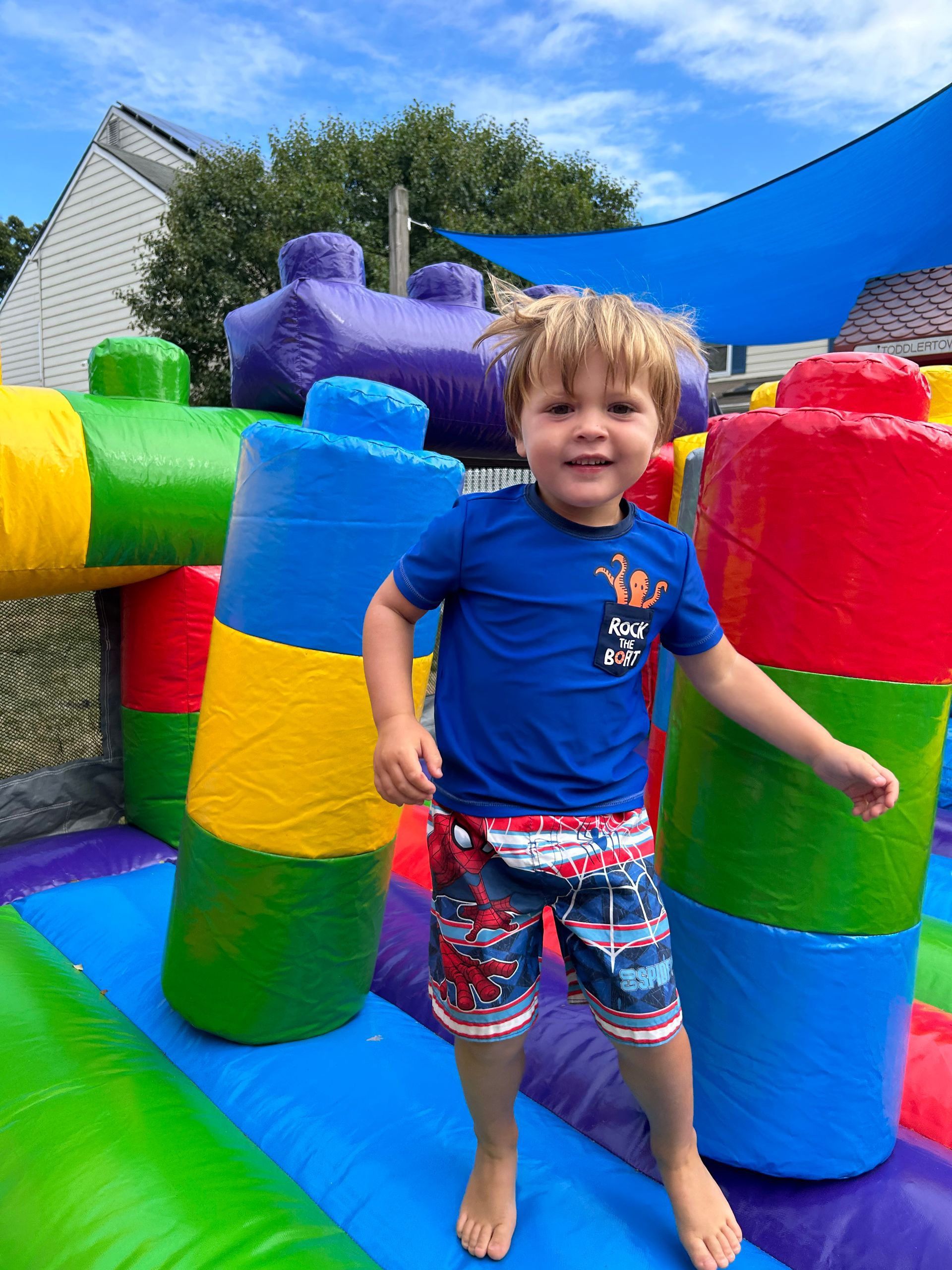 A young boy is standing on a colorful bouncy house.