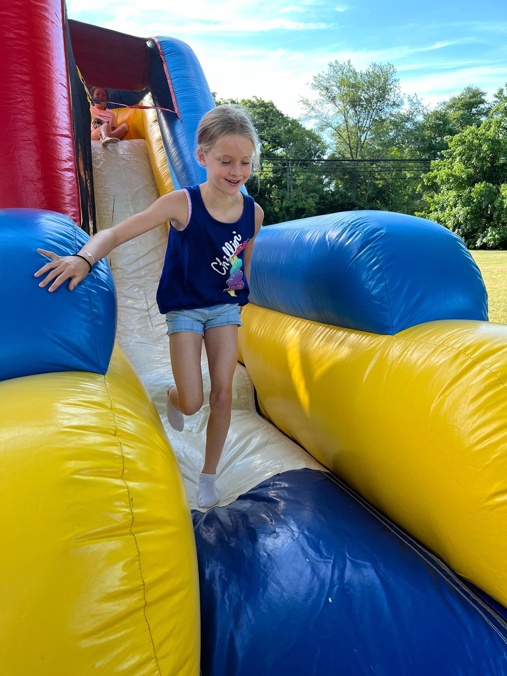 A little girl is playing on an inflatable slide.