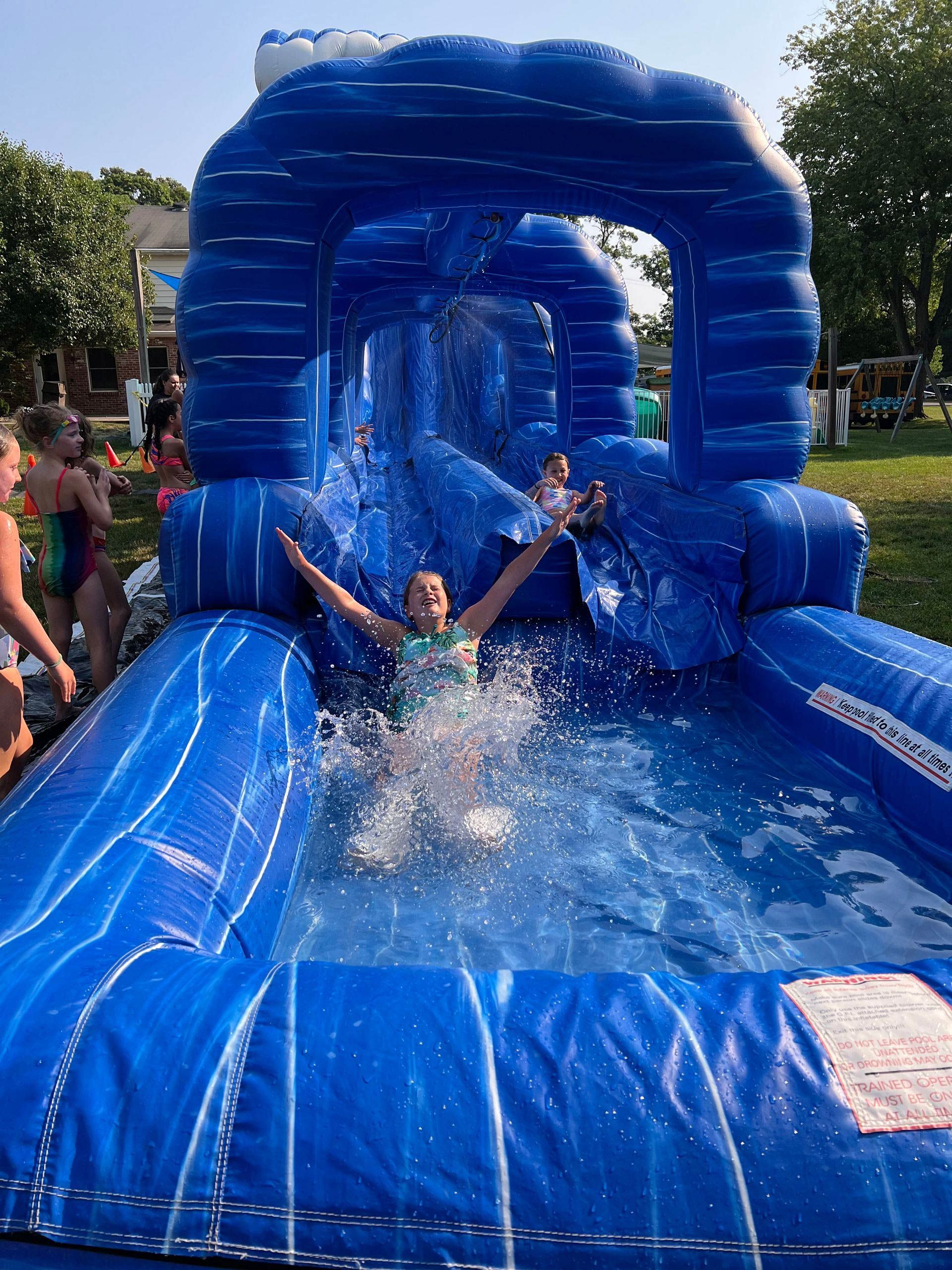 A girl is playing on an inflatable water slide.