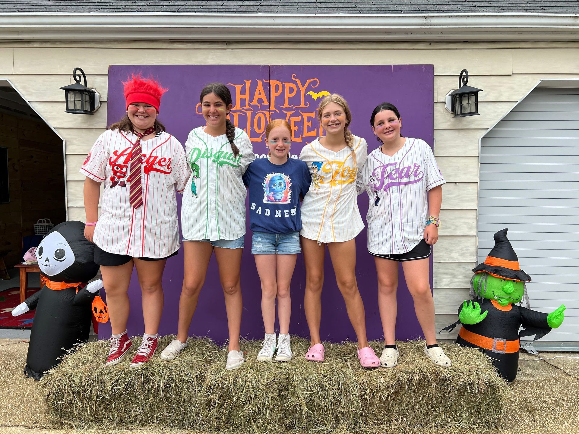 A group of young girls are posing for a picture in front of a happy halloween sign.