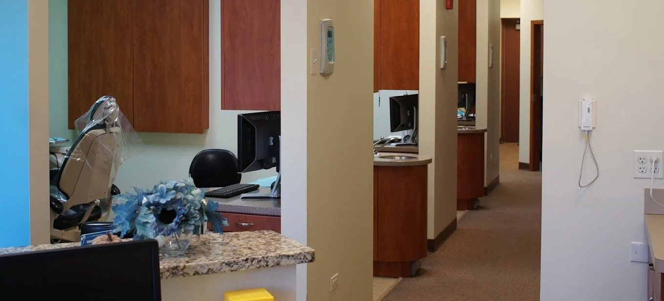 Interior view of an office hallway with dental stations and an administrative area visible.
