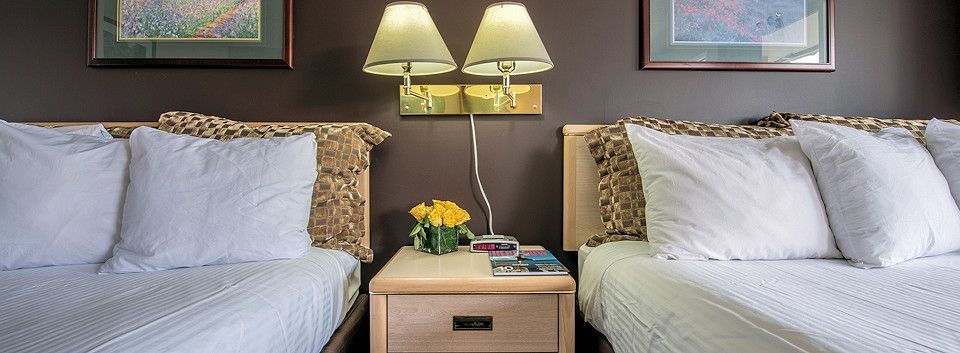 A hotel room with two beds and a nightstand.