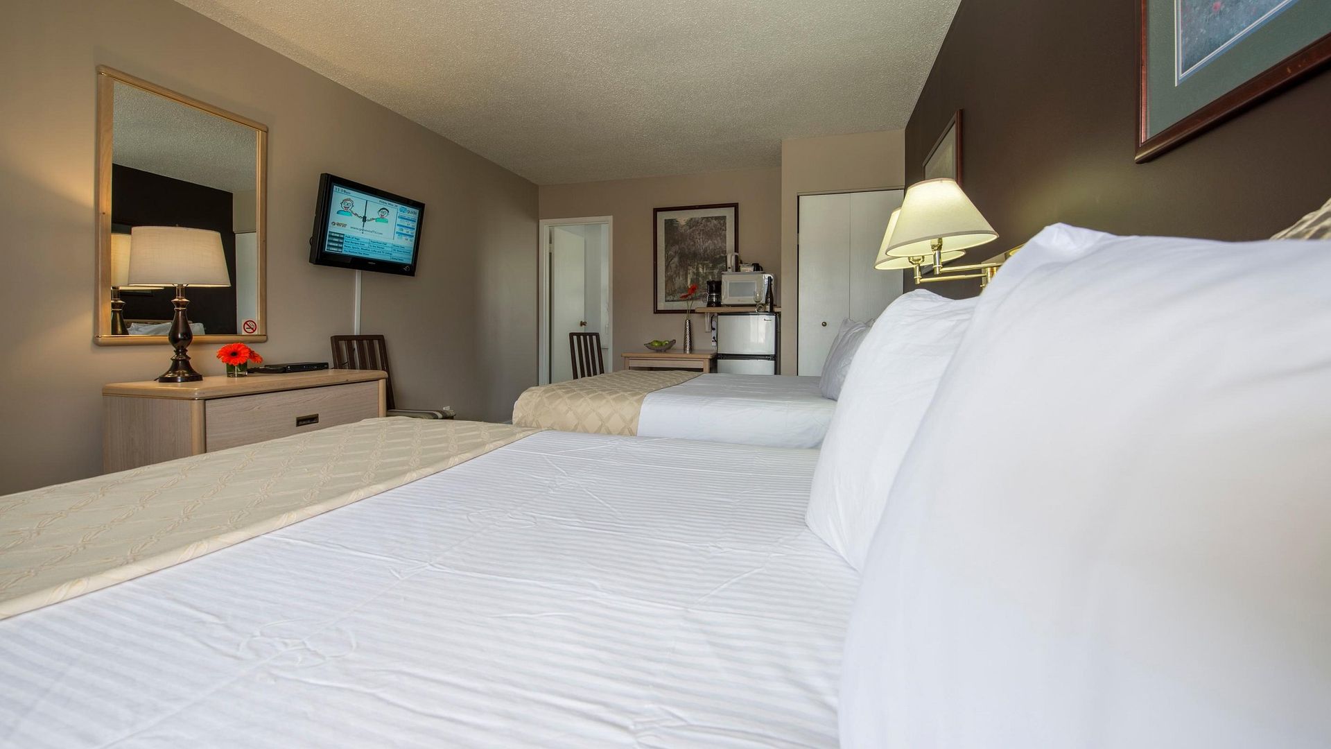 A hotel room with two beds and a flat screen tv