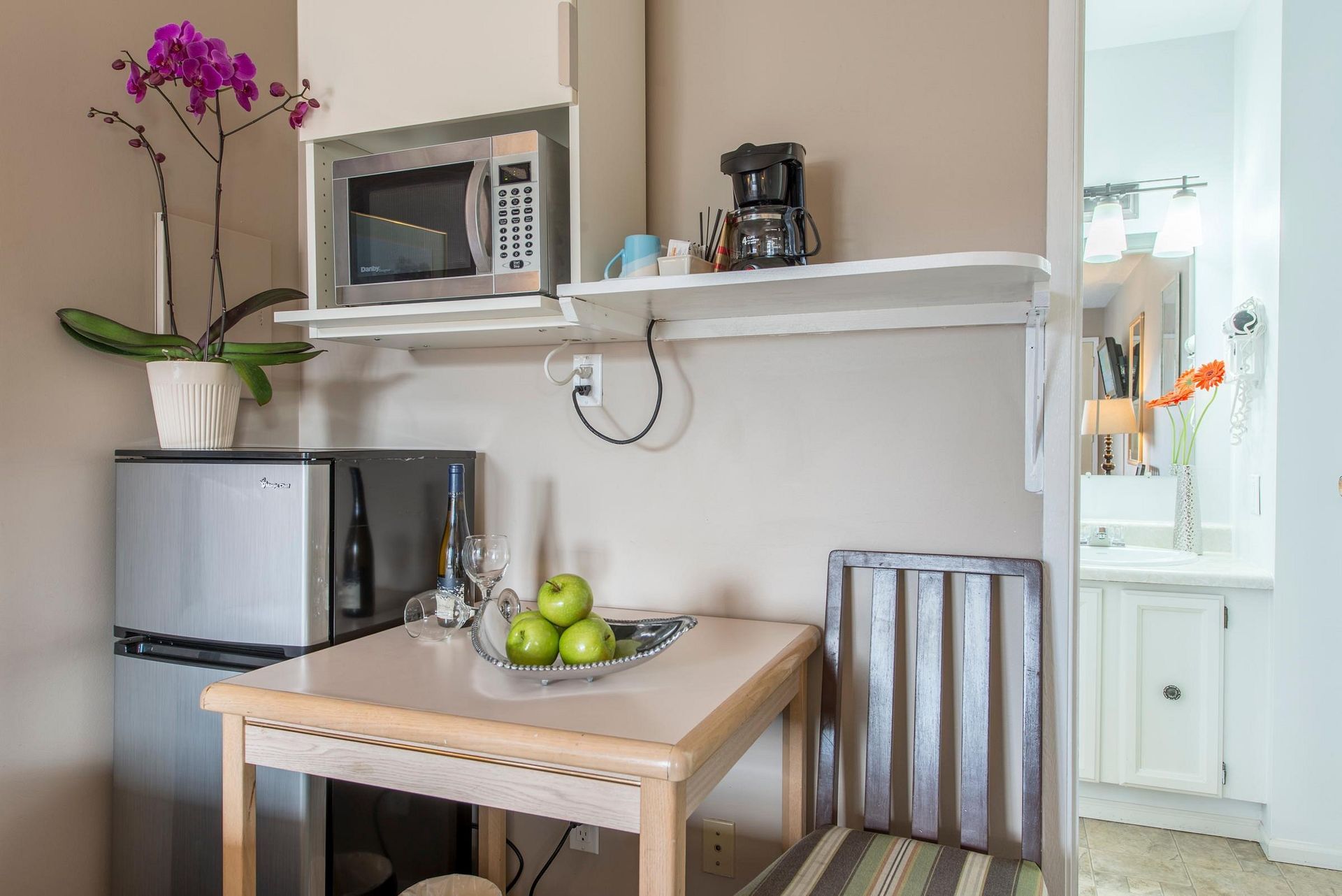 A small kitchen with a table , chair , microwave and refrigerator.