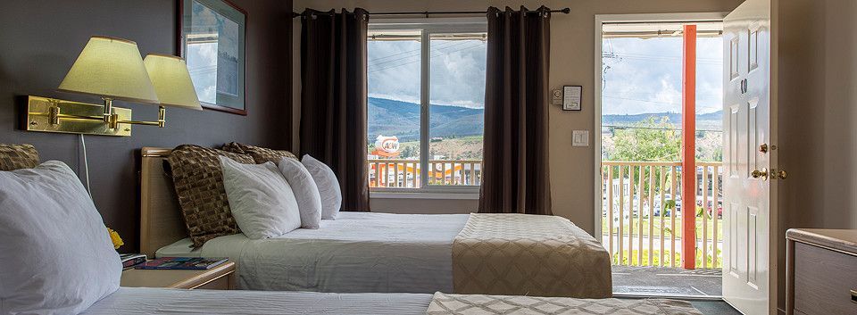 A hotel room with two beds and a balcony.