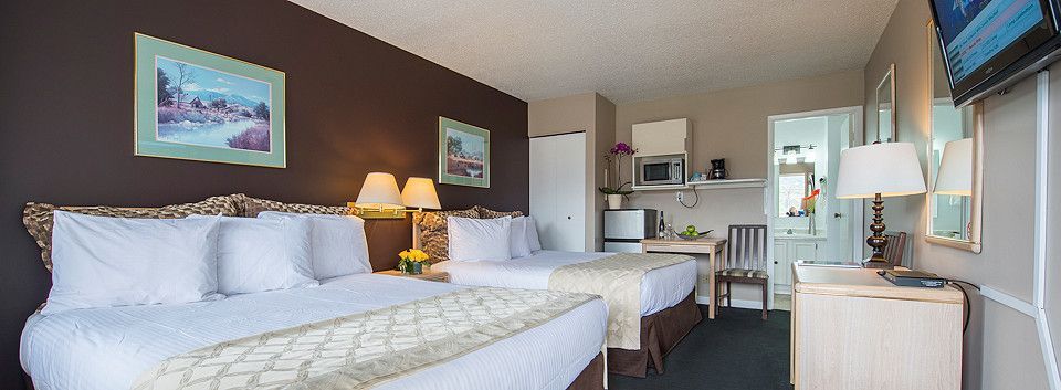 A hotel room with two beds , a desk and a television.