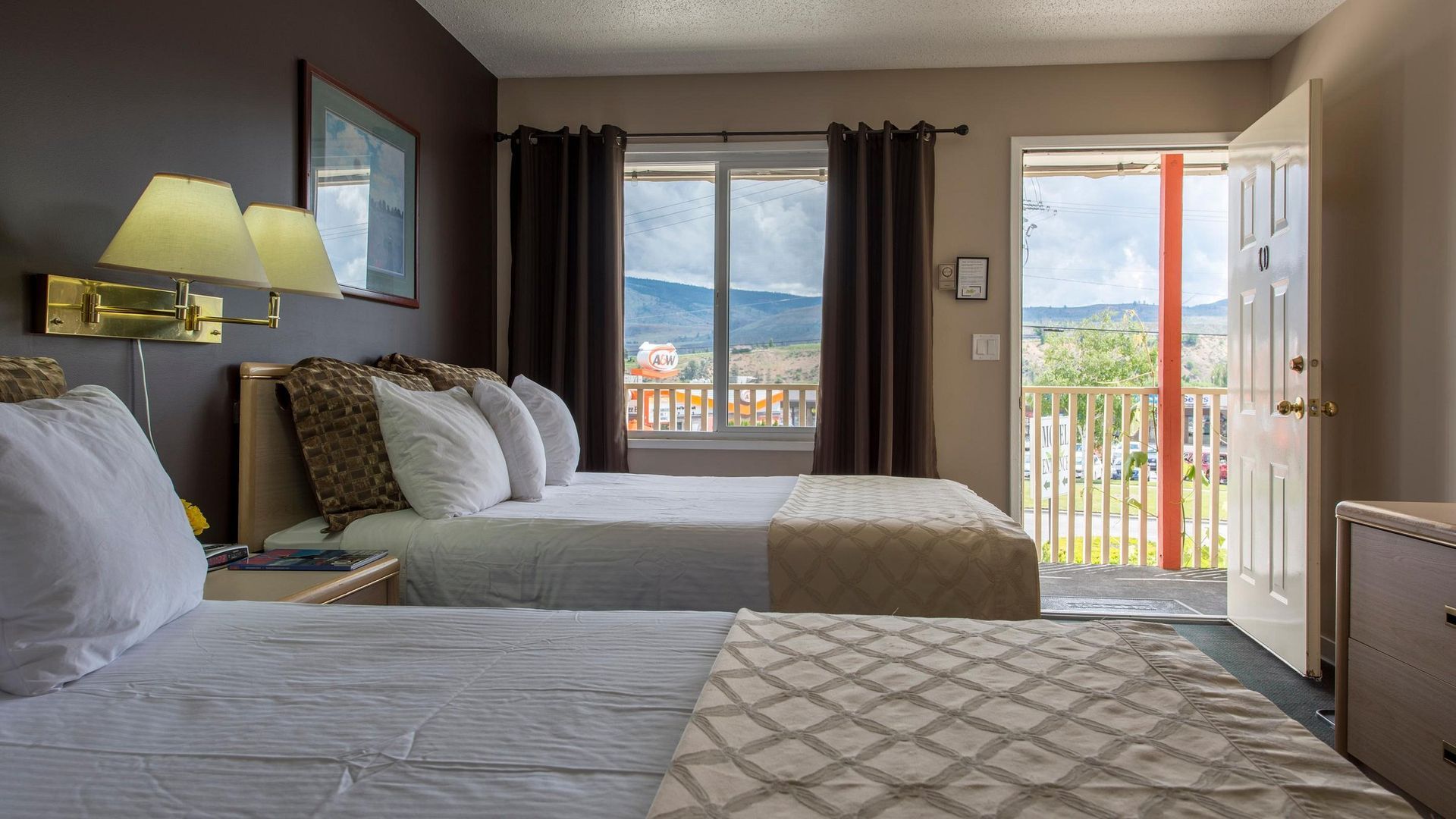 A hotel room with two beds and a balcony.