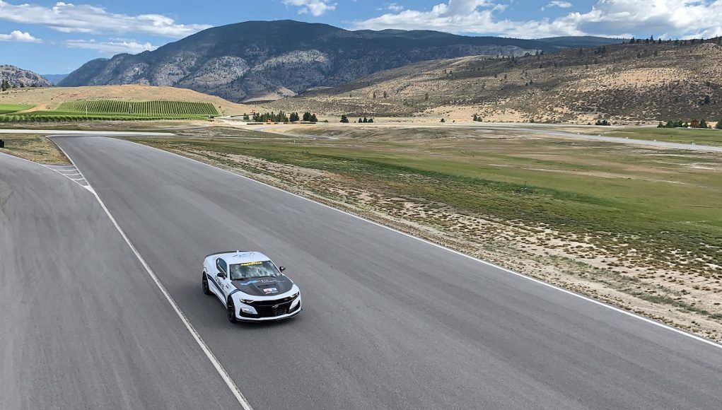 A car is driving down a road with mountains in the background.