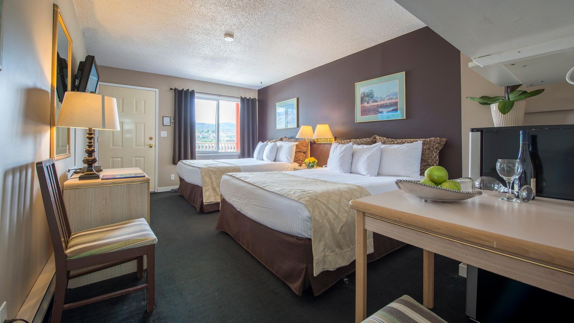 A hotel room with two beds , a table and chairs.