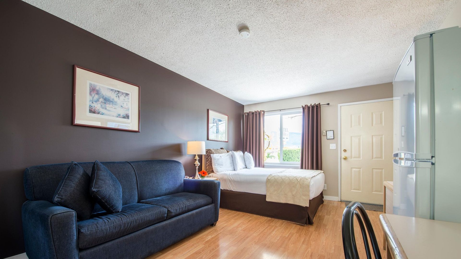 A hotel room with a couch , bed and desk.