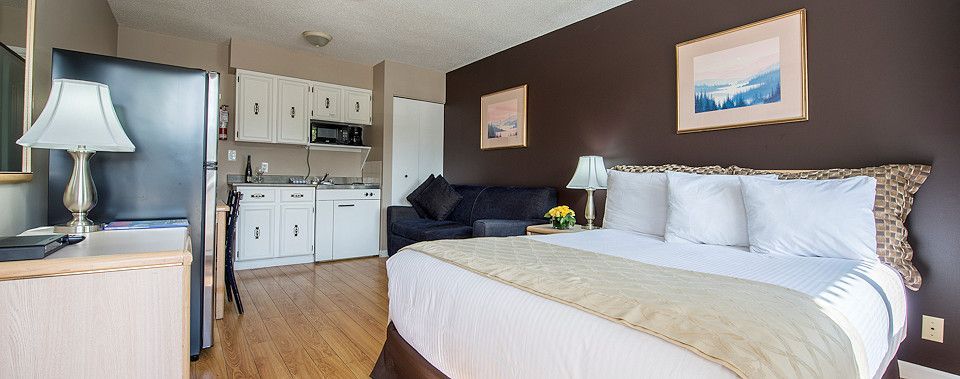 A hotel room with a king size bed and a kitchen.