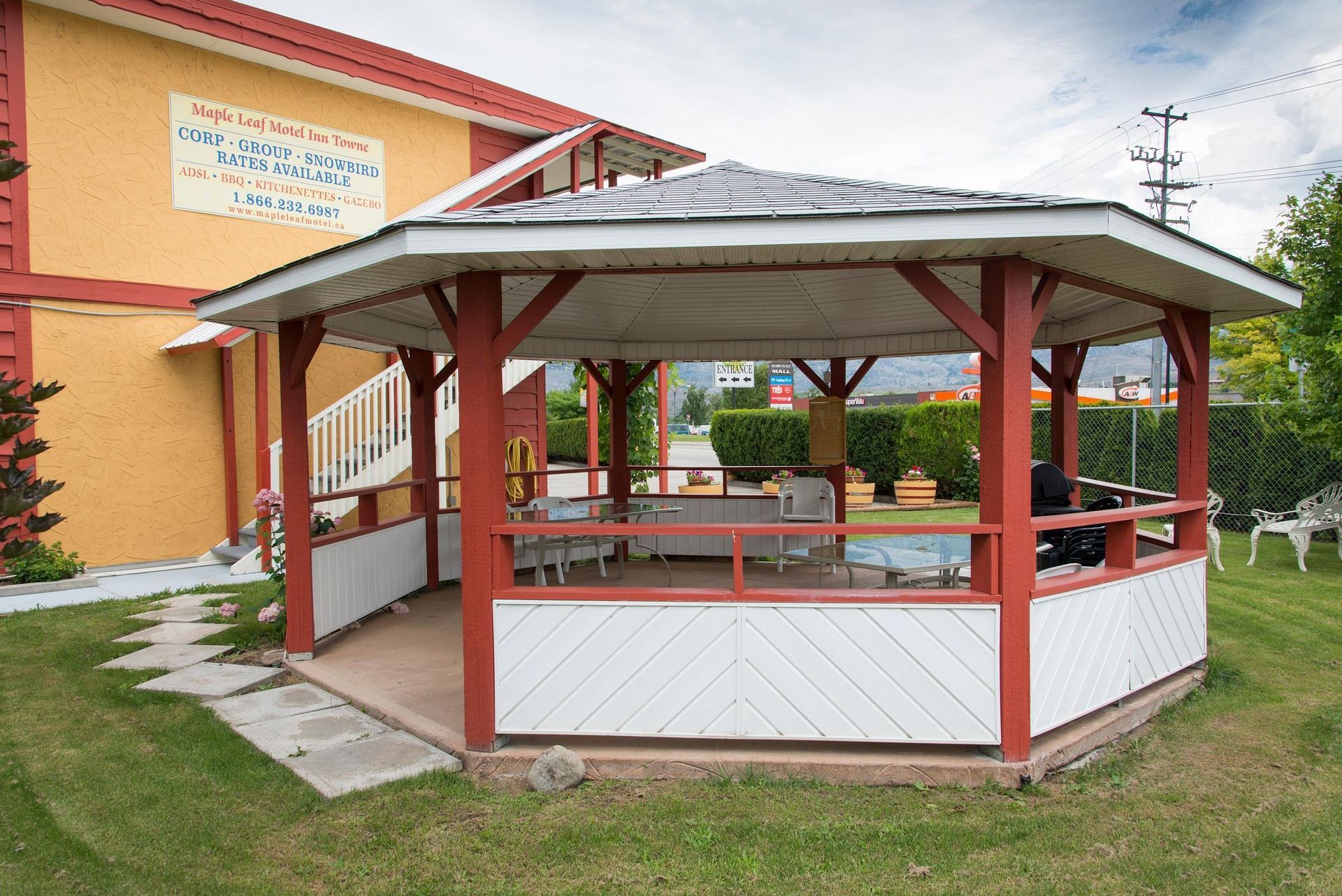 A gazebo with tables and chairs in front of a building.